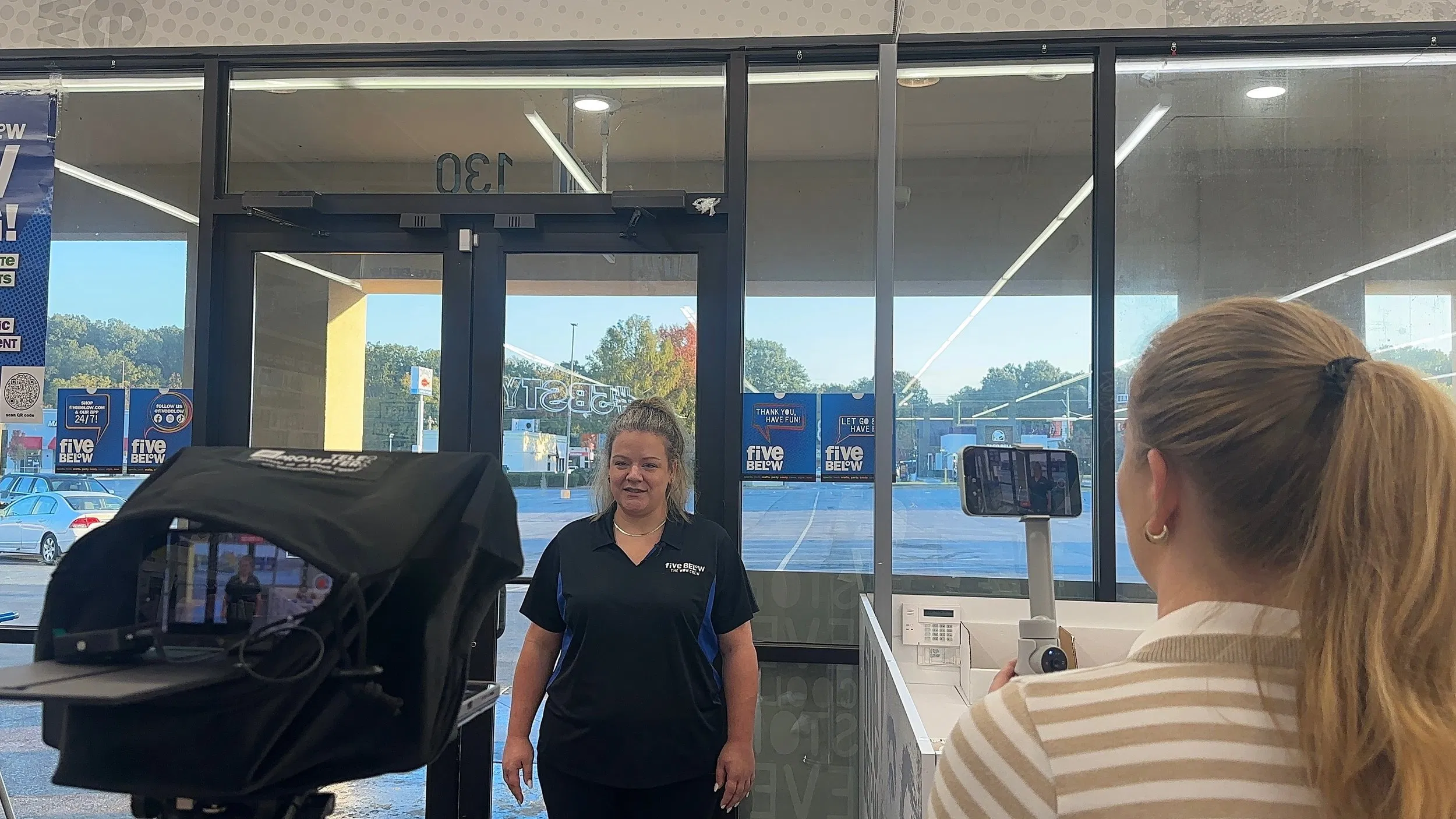 Behind-the-scenes of a Blue Plate Production shoot at a store entrance, featuring professional lighting and a smartphone gimbal for authentic video content.