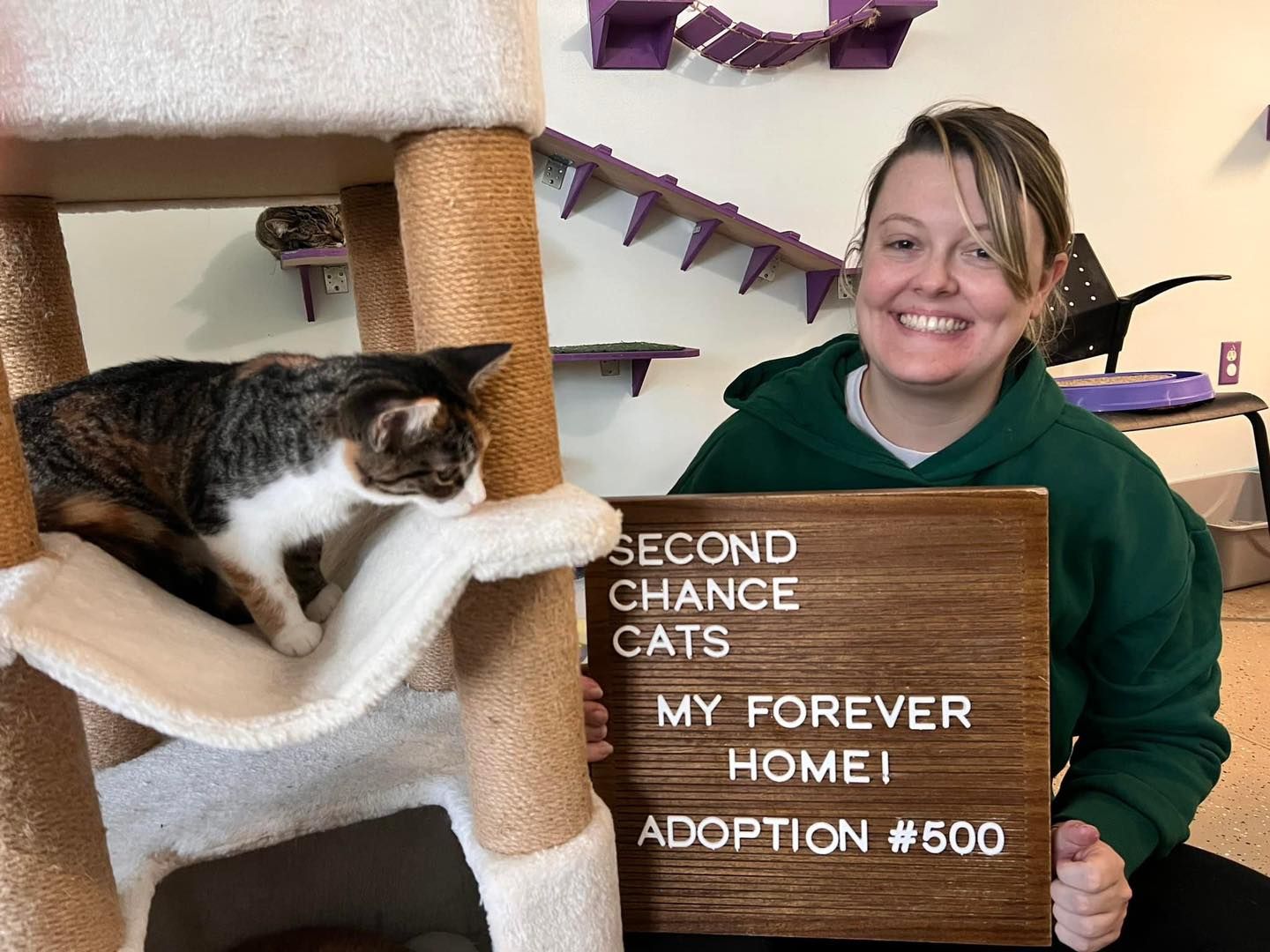 A smiling volunteer celebrating the 500th adoption at Second Chance Cats, showing the joy of finding forever homes.