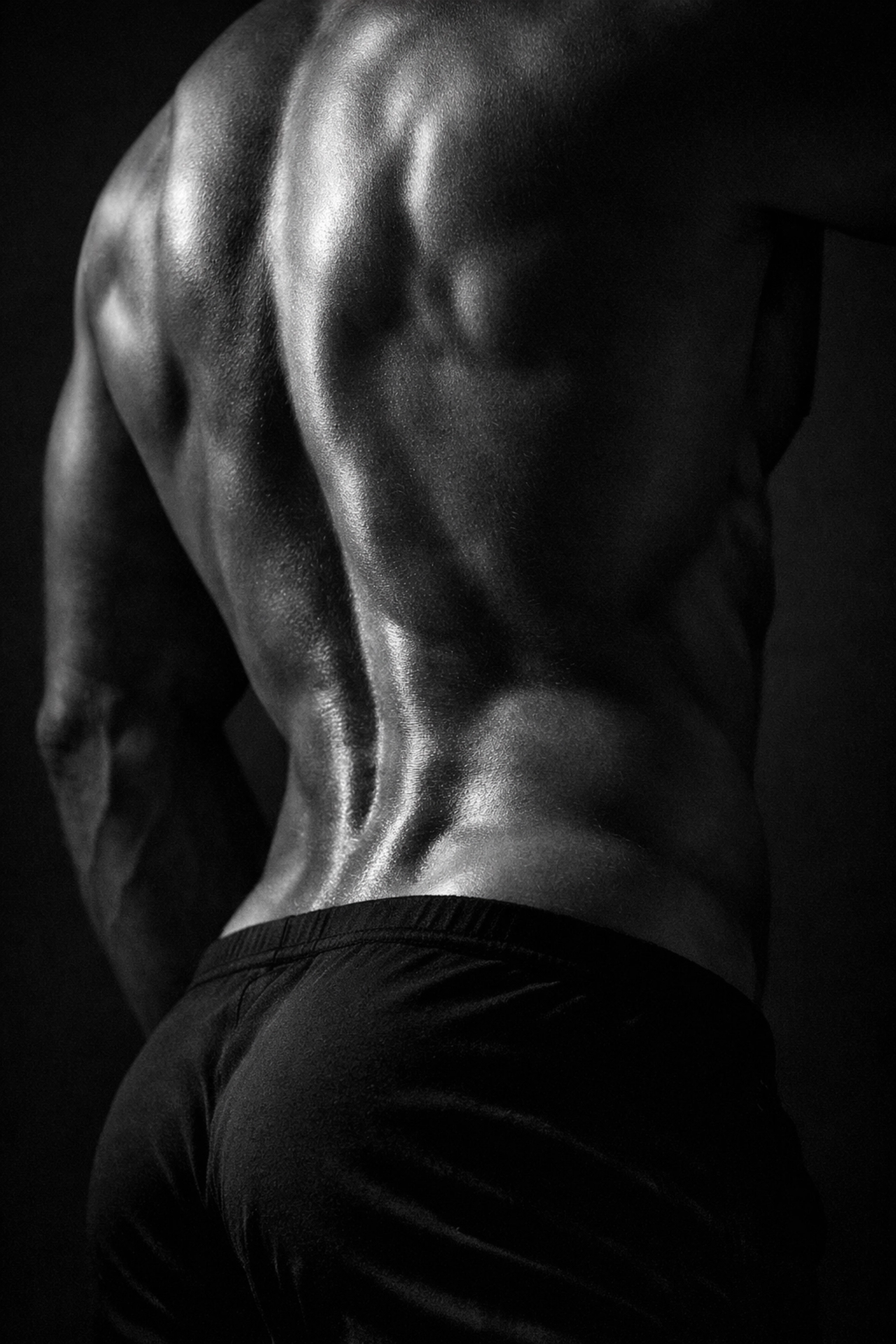 Artistic black and white photo of a man’s lumbar curve and lower back muscles.