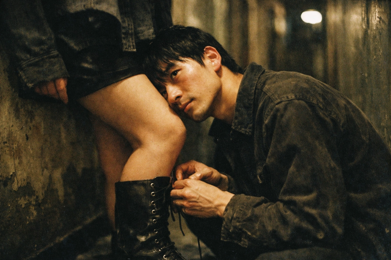 East Asian man in a dim hallway, kneeling to tie a partner’s boots, cheek against their knee, longing eye contact, raw natural light, 35mm grit