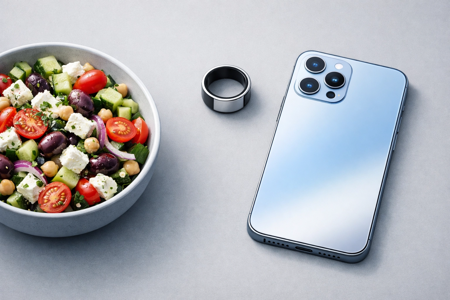 A smart ring and phone next to a healthy salad representing AI-driven personalized meal planning.