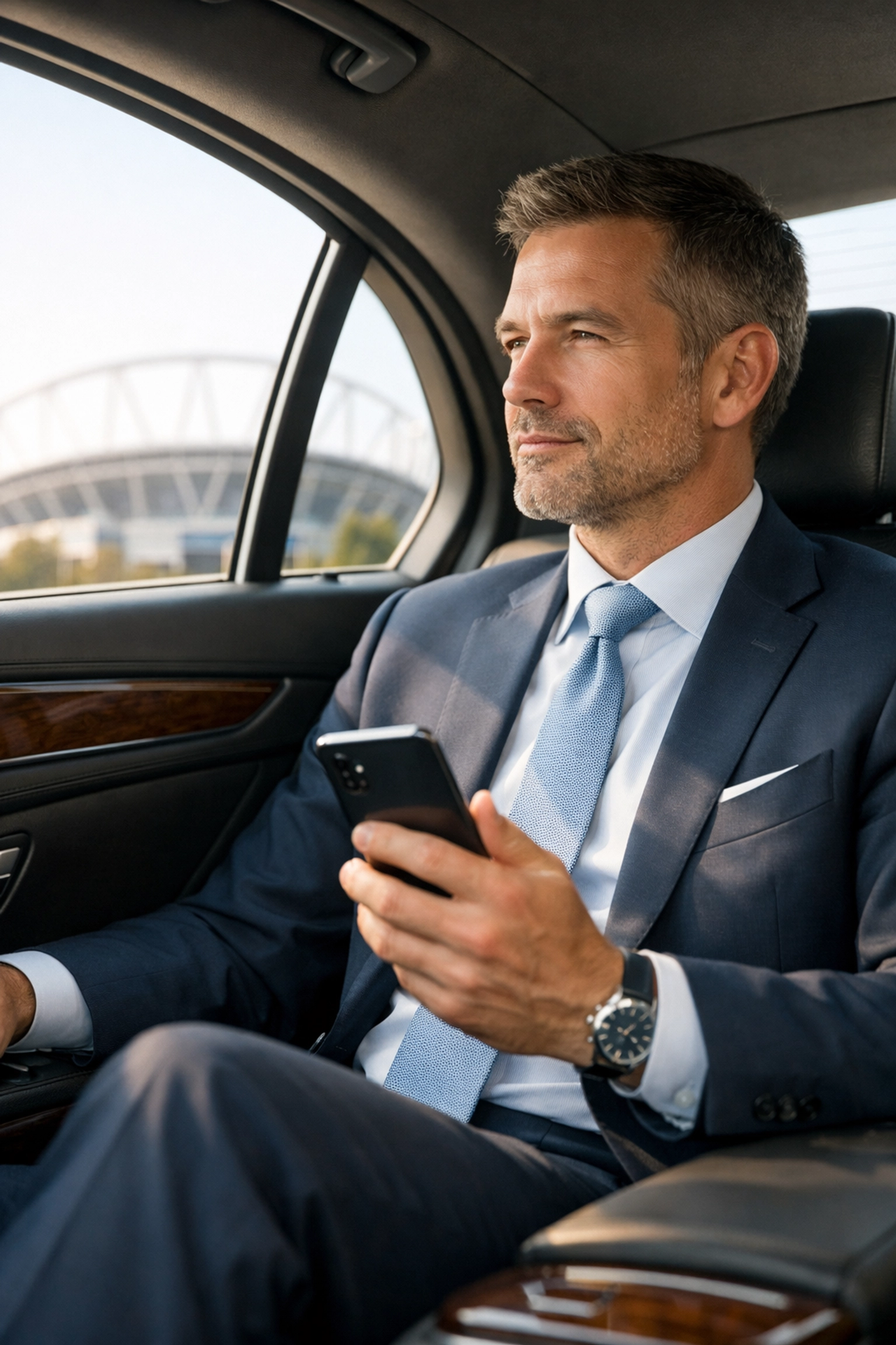 Executive traveling in a luxury vehicle toward a stadium for Super Bowl corporate networking.