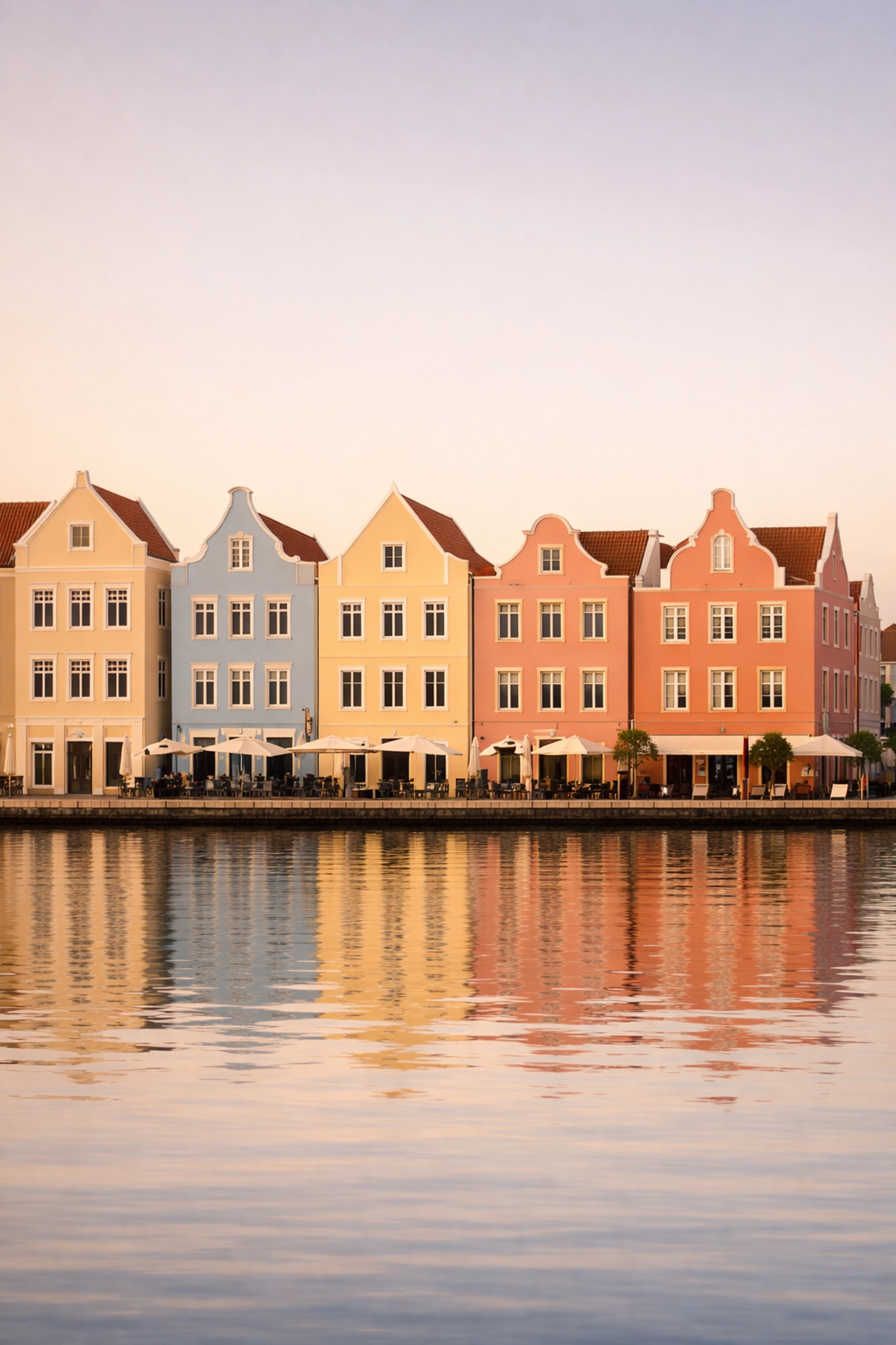 The colorful Dutch colonial buildings of Willemstad, Curaçao, glowing under the golden hour sun at Handelskade.