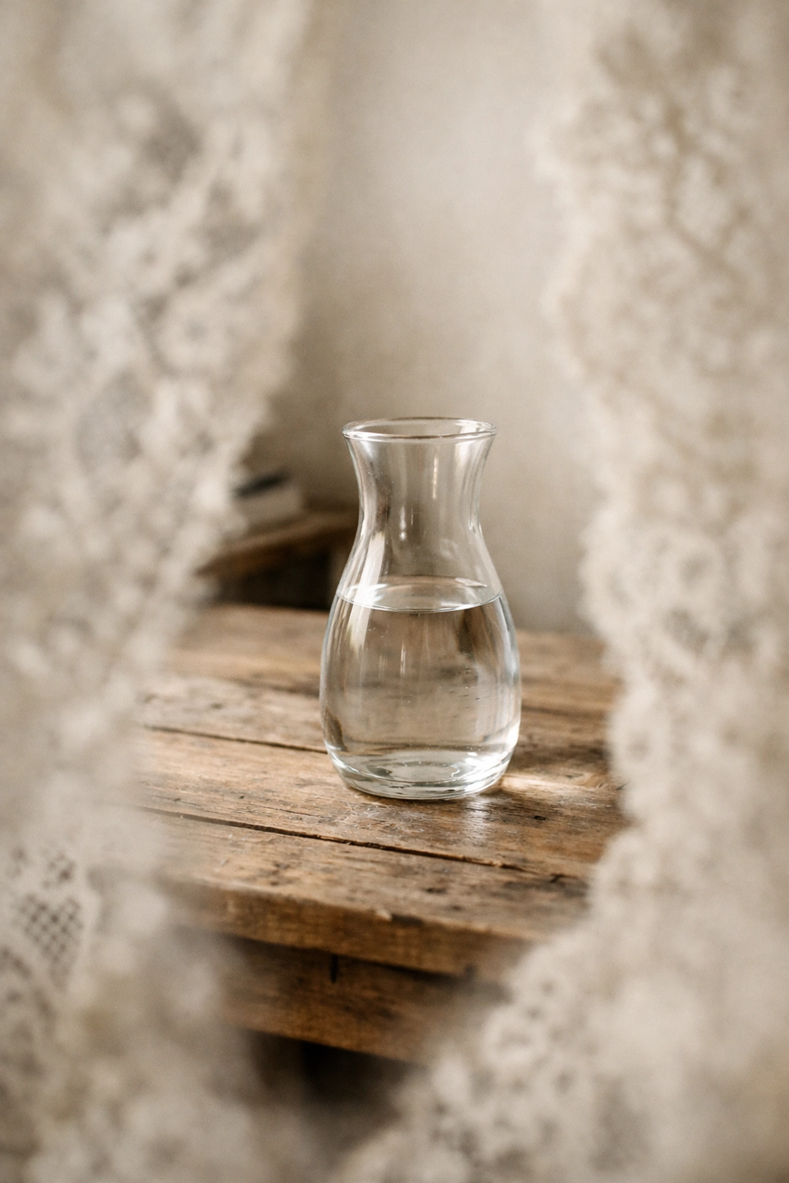 Ethereal photography shoot-through technique with soft lace foreground and glass carafe.