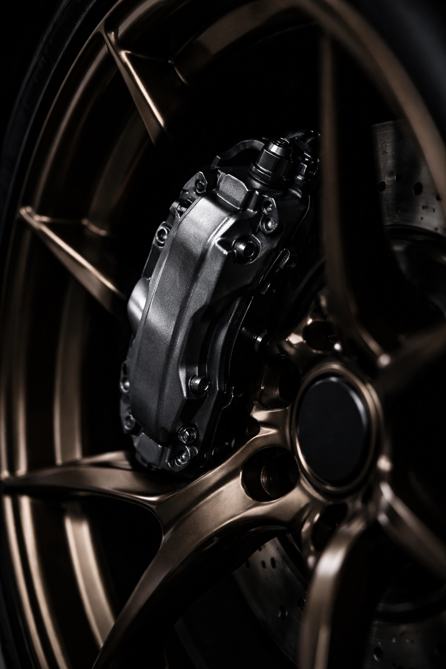 Gunmetal grey powder-coated caliper behind bronze wheel, illustrating sleek dark color customization