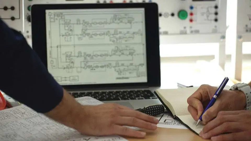 Two team members reviewing and drawing network schematics at a desk, highlighting Rodeo Networks' expertise in designing reliable solutions
