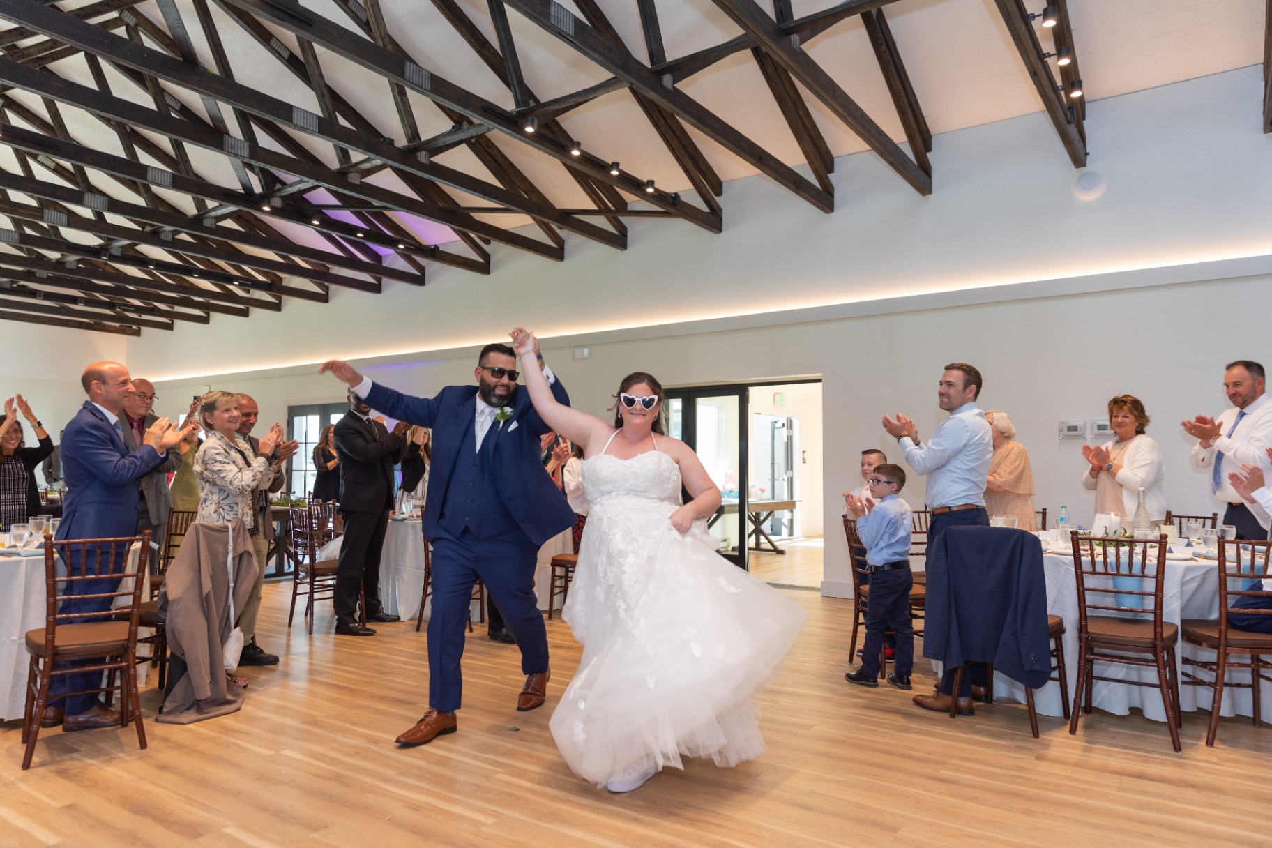 Natalie and Pat making their wedding entrance—sunglasses on, hands up, pure celebration