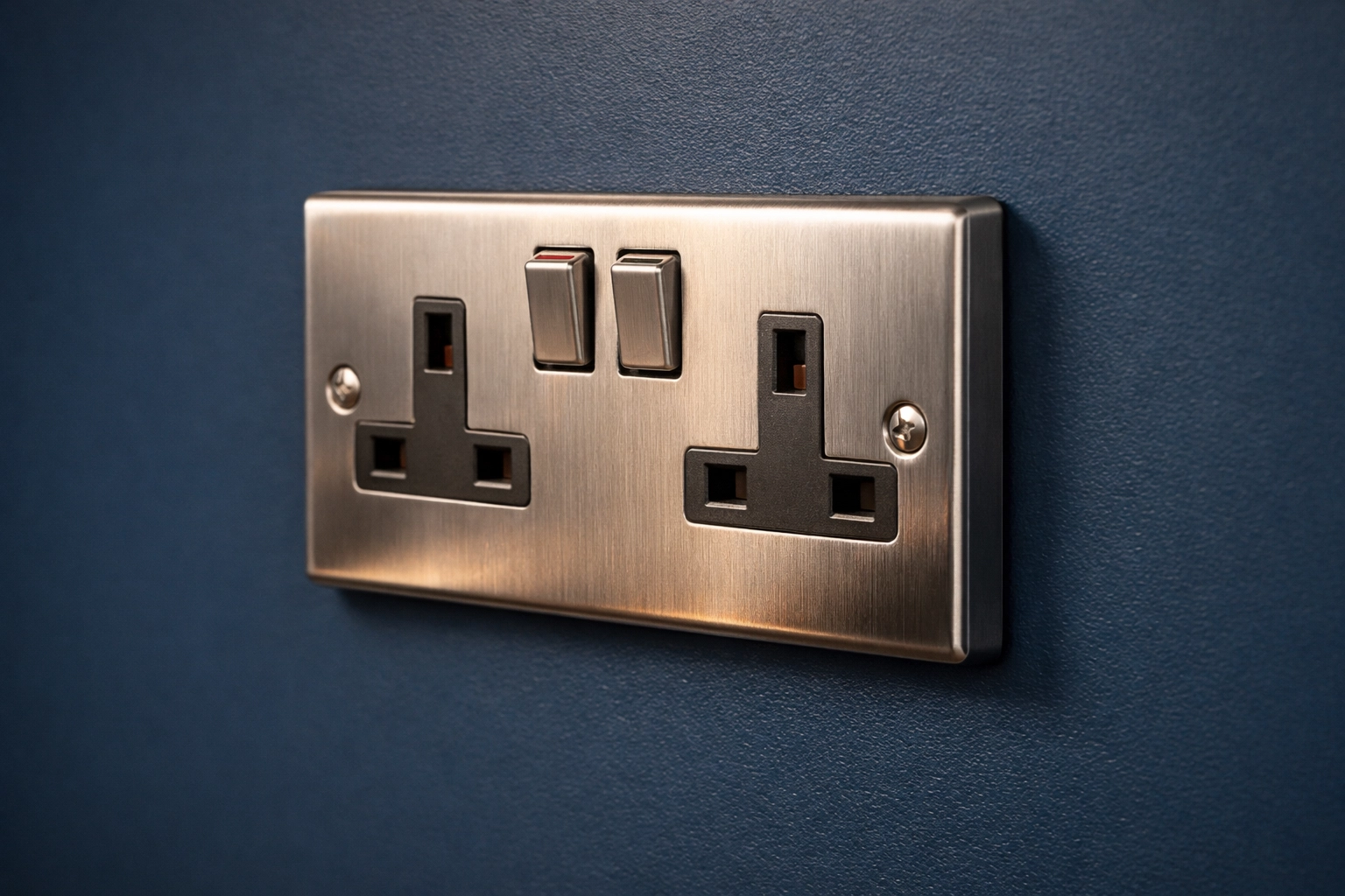 Professional installation of a brushed chrome UK double socket on a navy wall by electricians in Poole.