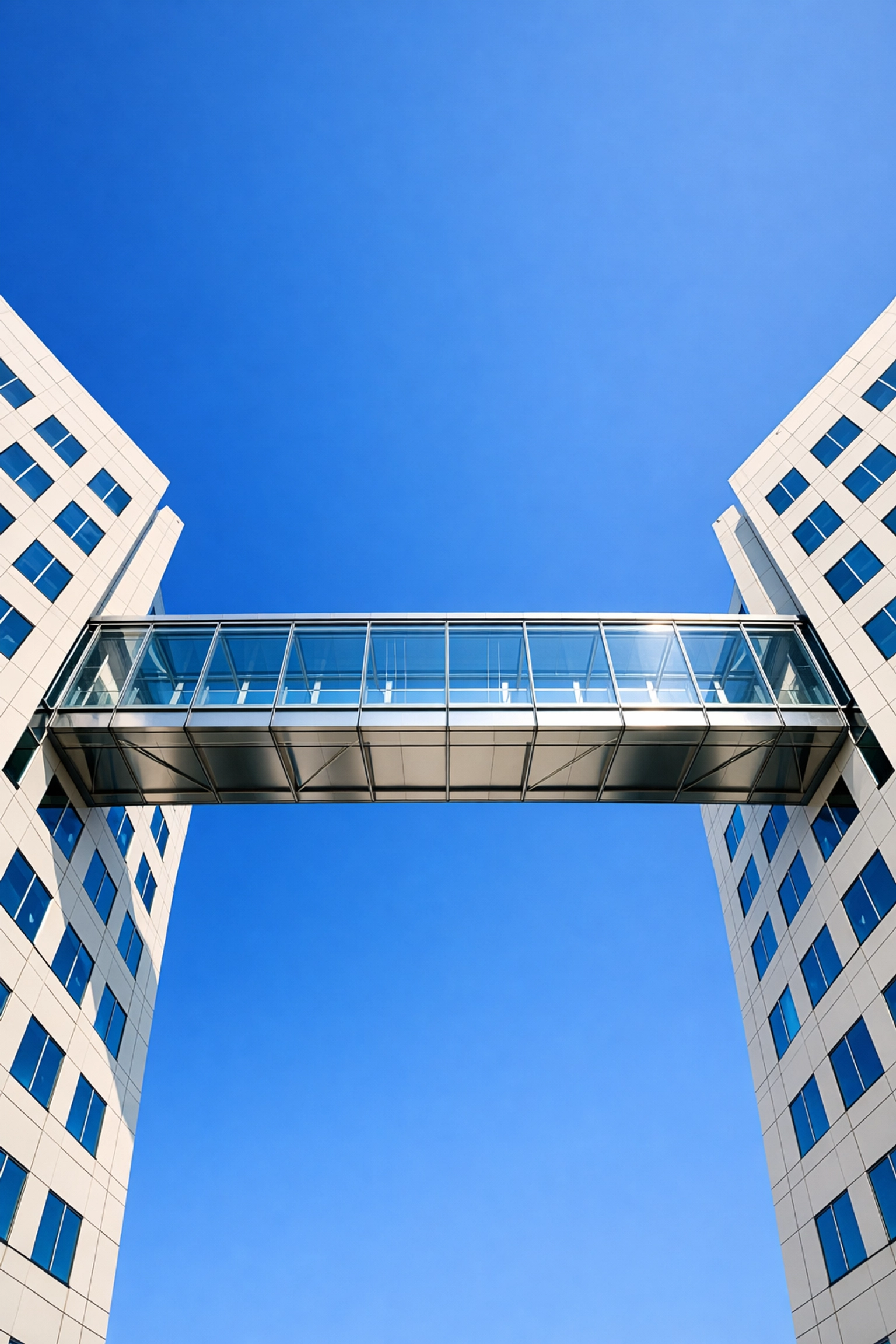 Modern glass bridge connecting buildings, symbolizing a factoring line bridging the cash flow gap.