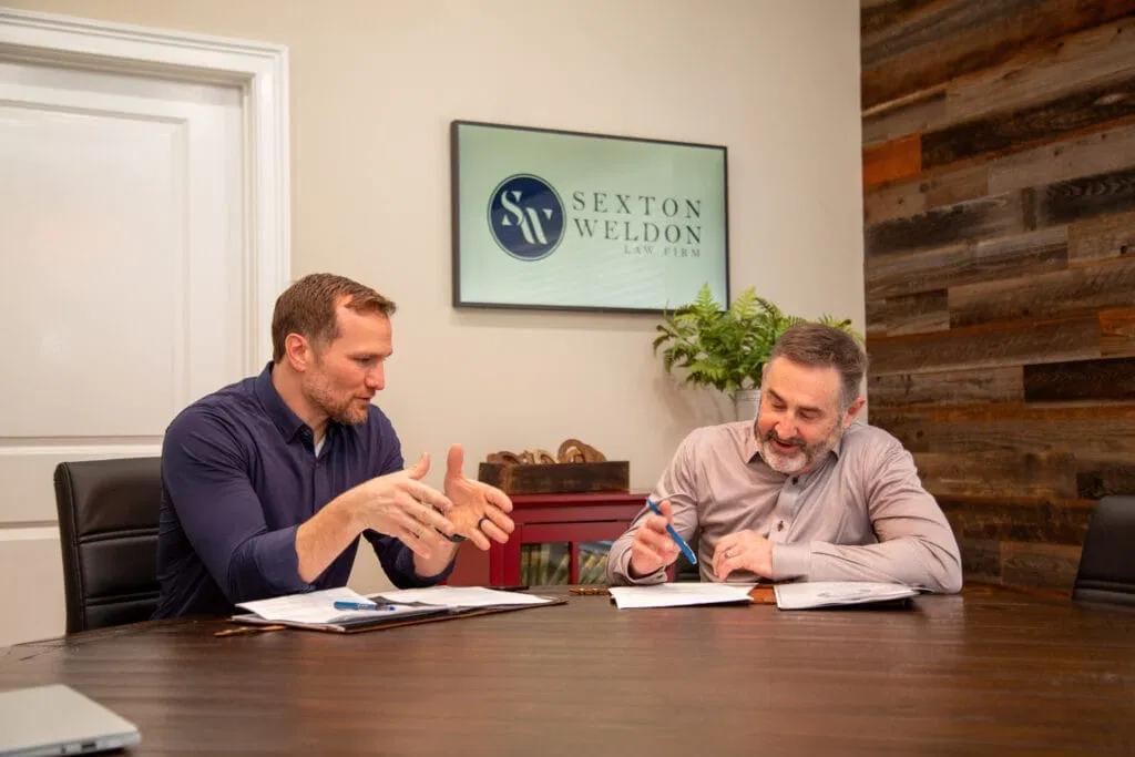 Two attorneys at Sexton Weldon Law Firm collaborate over paperwork in a conference room