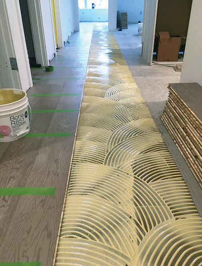 Engineered hardwood flooring glue-down installation in progress