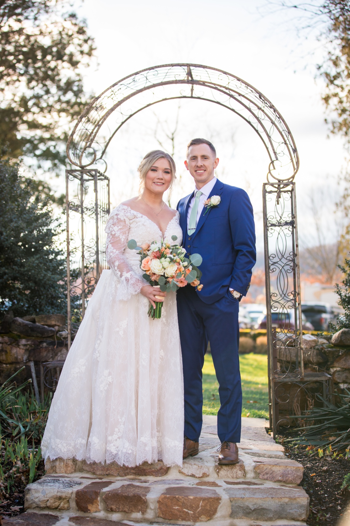 Bride and groom pose together under a wrought iron garden arch