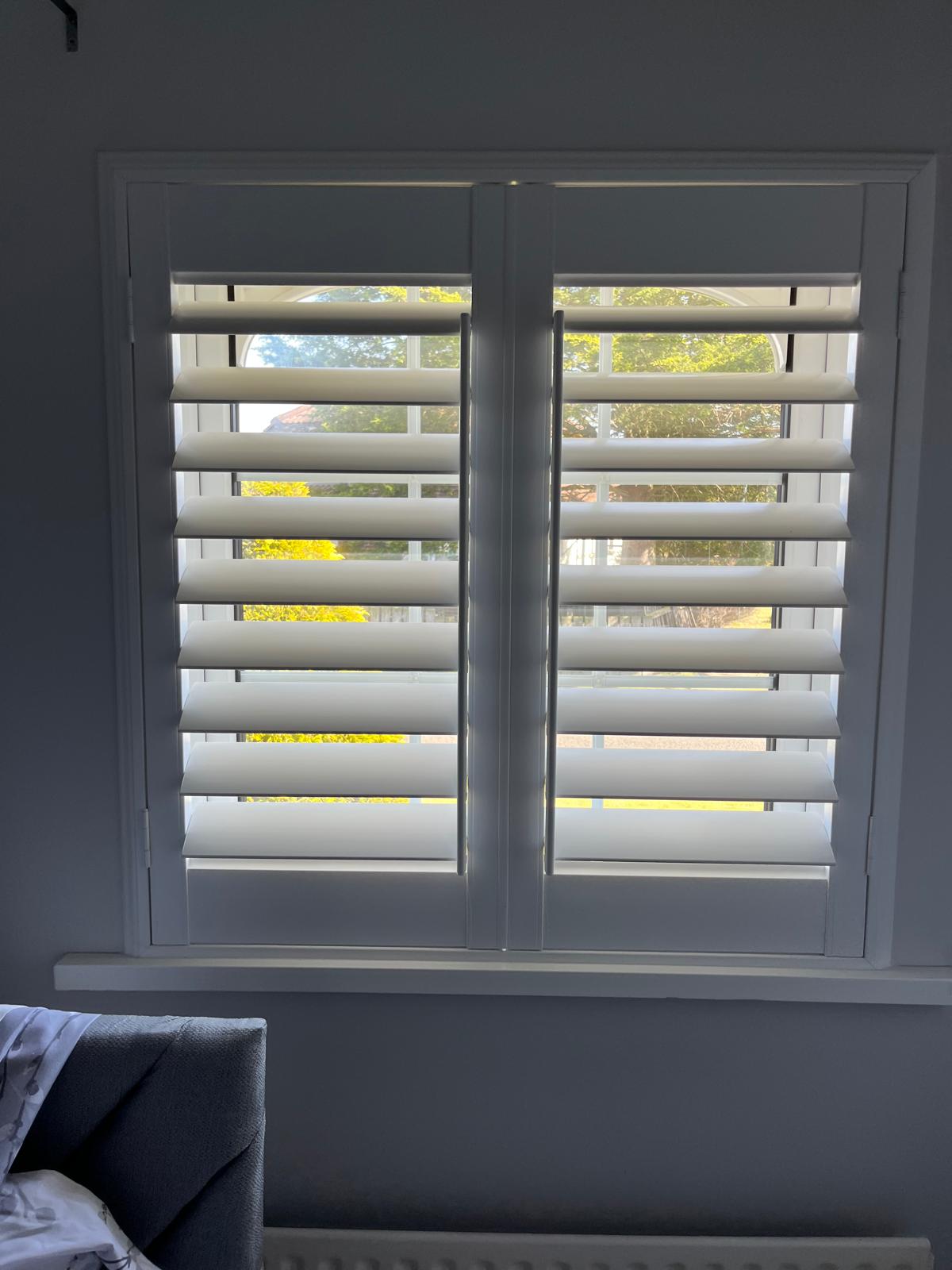 Custom-made white plantation shutters professionally installed on a double window