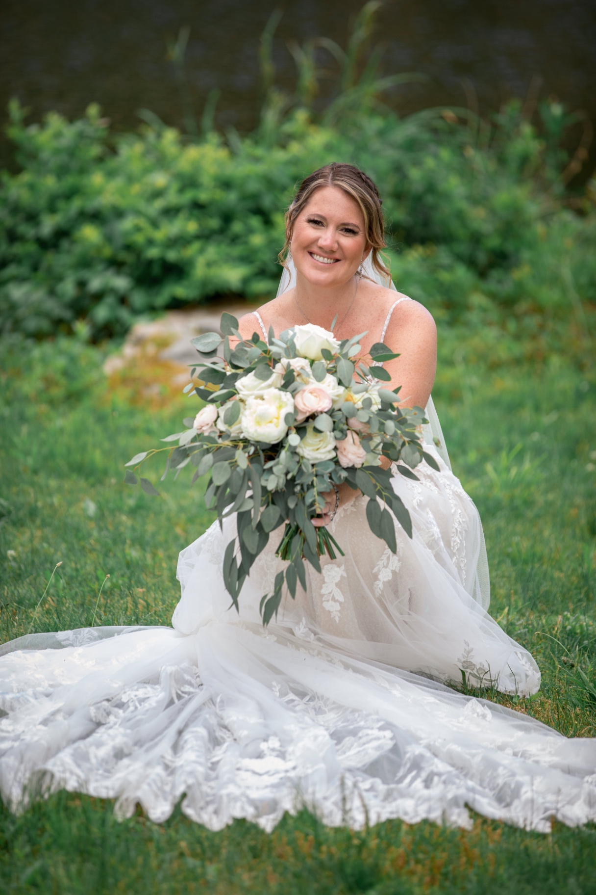 Bride in a lace wedding gown outdoors by the water