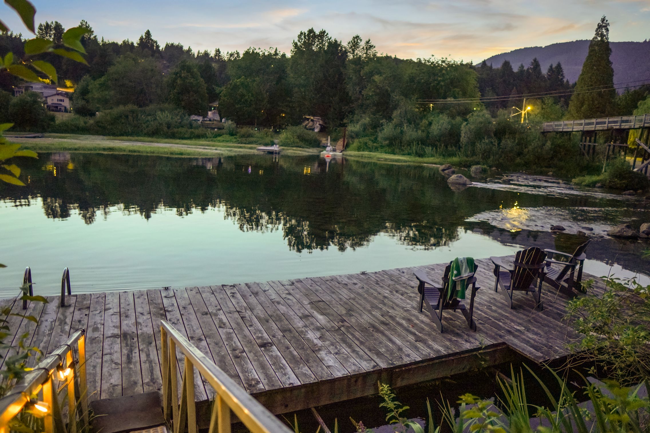 Riverside firepit and gathering area at Cowichan Lake Cottages Real riverside common area with a firepit, seating, and warm evening vibes for guests to unwind together.