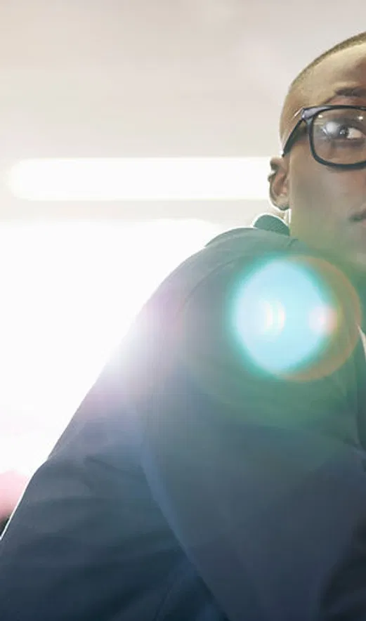 Close-up of a person in a dark custom sweatshirt, with a modern, minimal look and sunlight flare in the background.