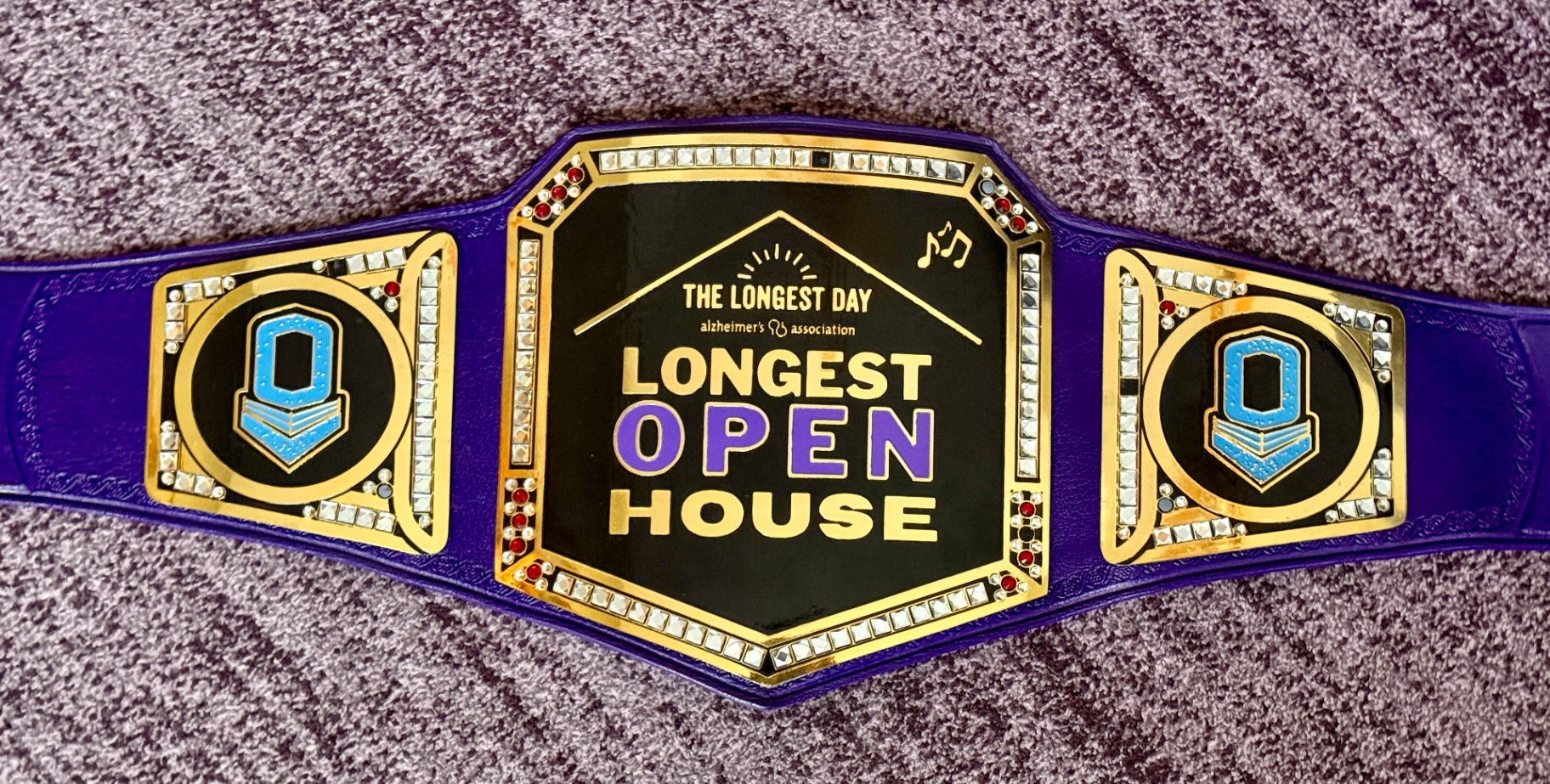 The custom “In Your Open House” championship belt—purple strap, gold trim, and Alzheimer’s Association branding
