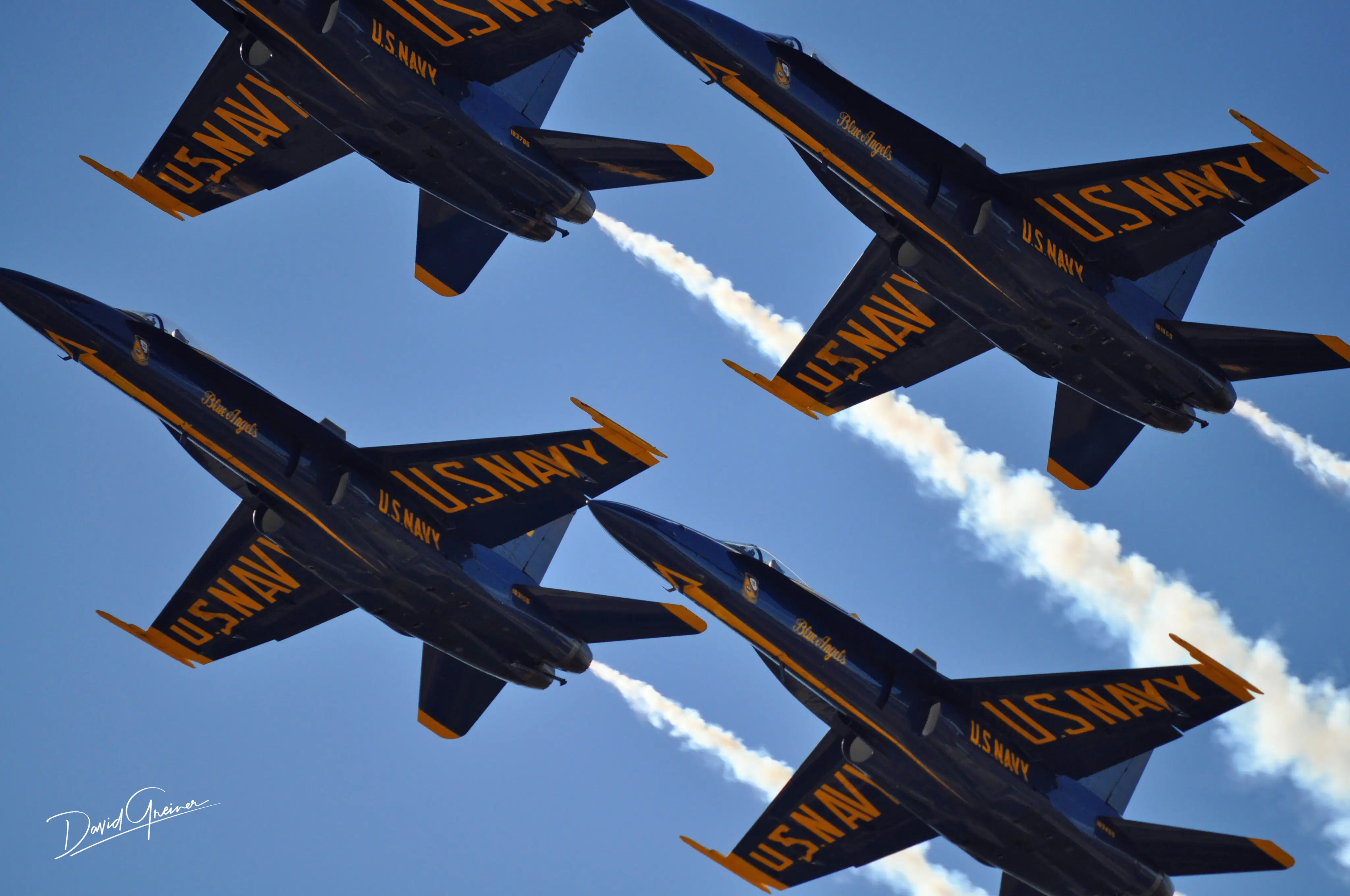 Four U.S. Navy Blue Angels jets flying in tight formation against a clear blue sky, representing precision and teamwork.