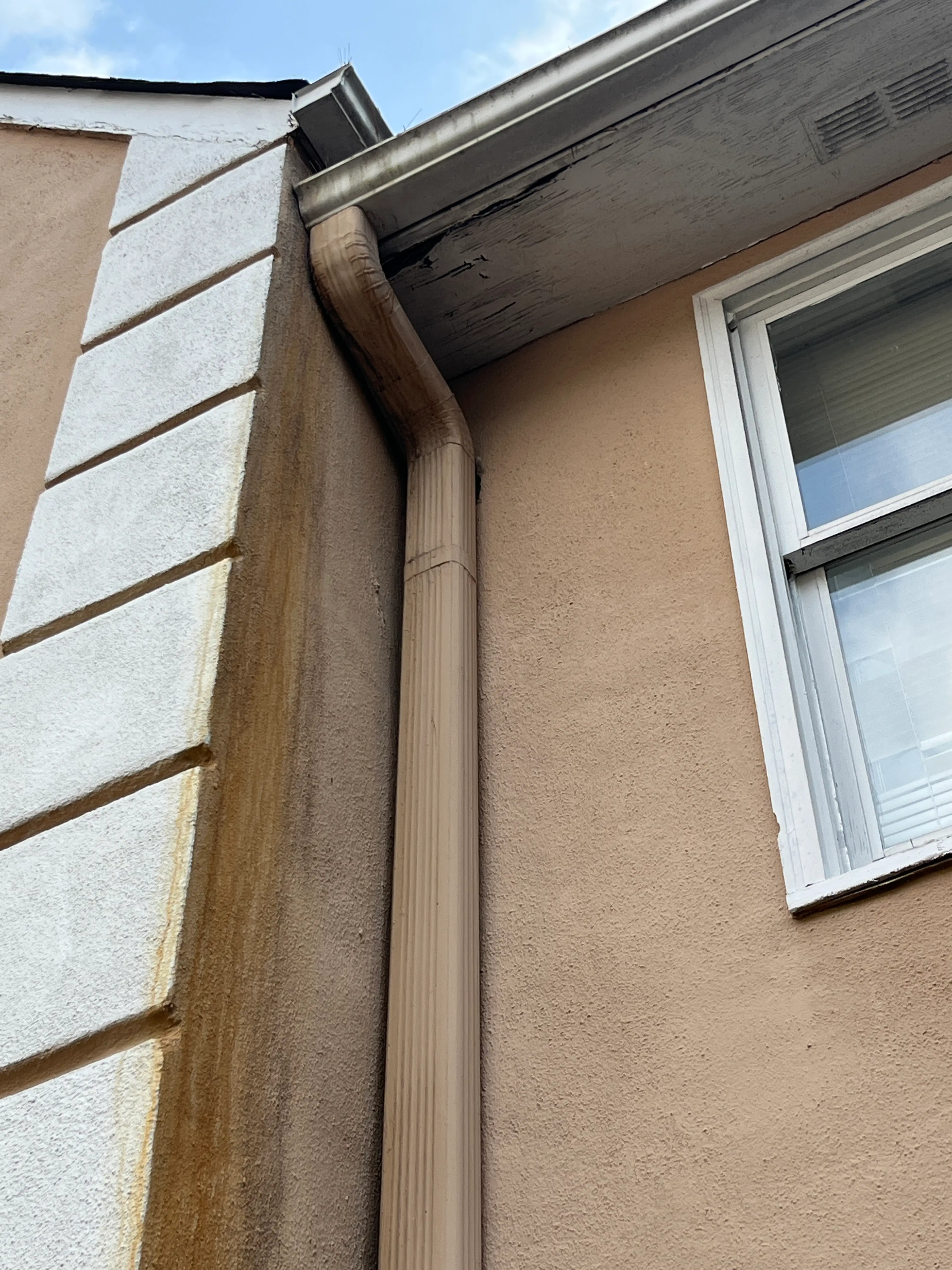 Close-up of damaged gutters and soffit with water stains and mold growth on an Atlanta rental property