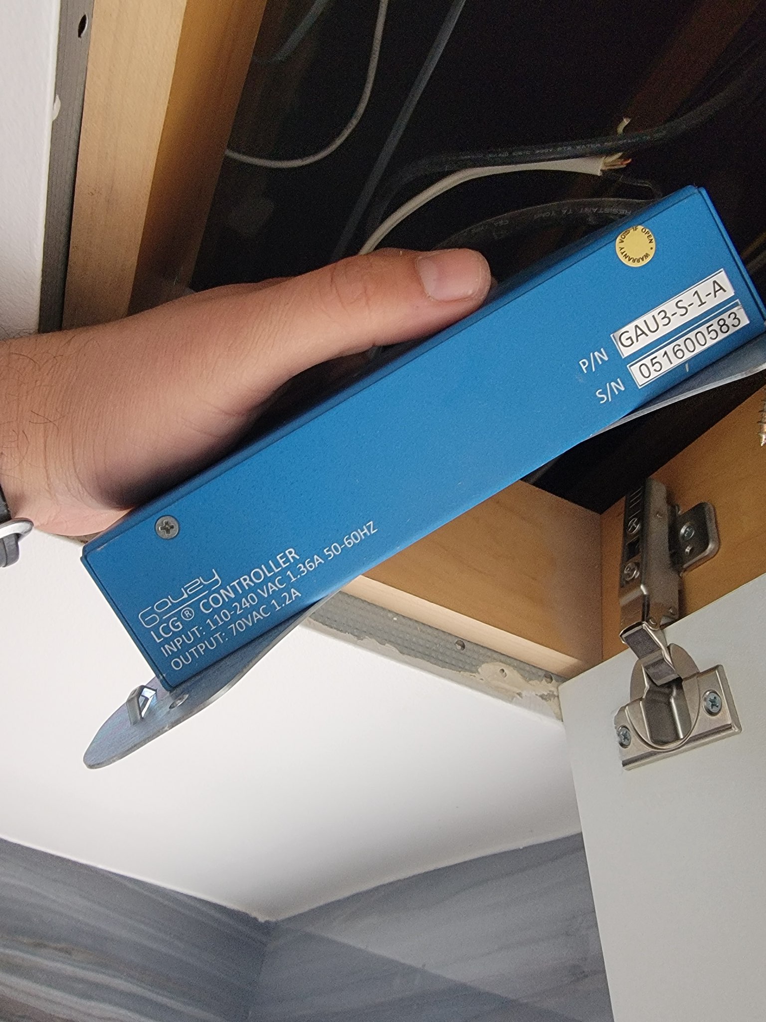 Technician installing a blue LCG controller during smart glass technical repair and PDLC system service