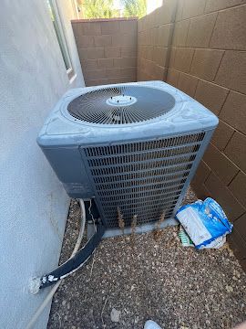 An outdoor AC unit sitting on gravel shows signs of dust buildup and wear, highlighting the need for a professional spring tune-up.