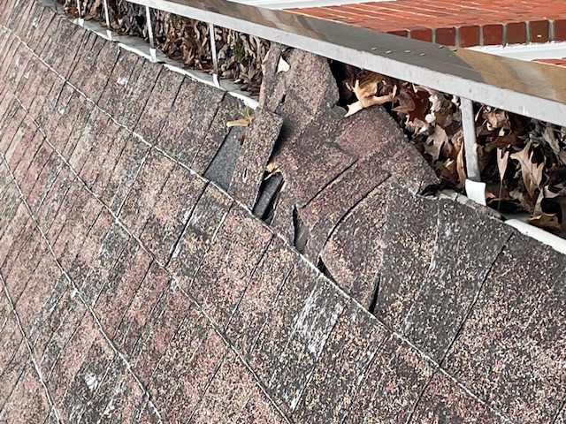 Asphalt shingles failing because they were installed over asbestos tile (tile cracked and lost support)