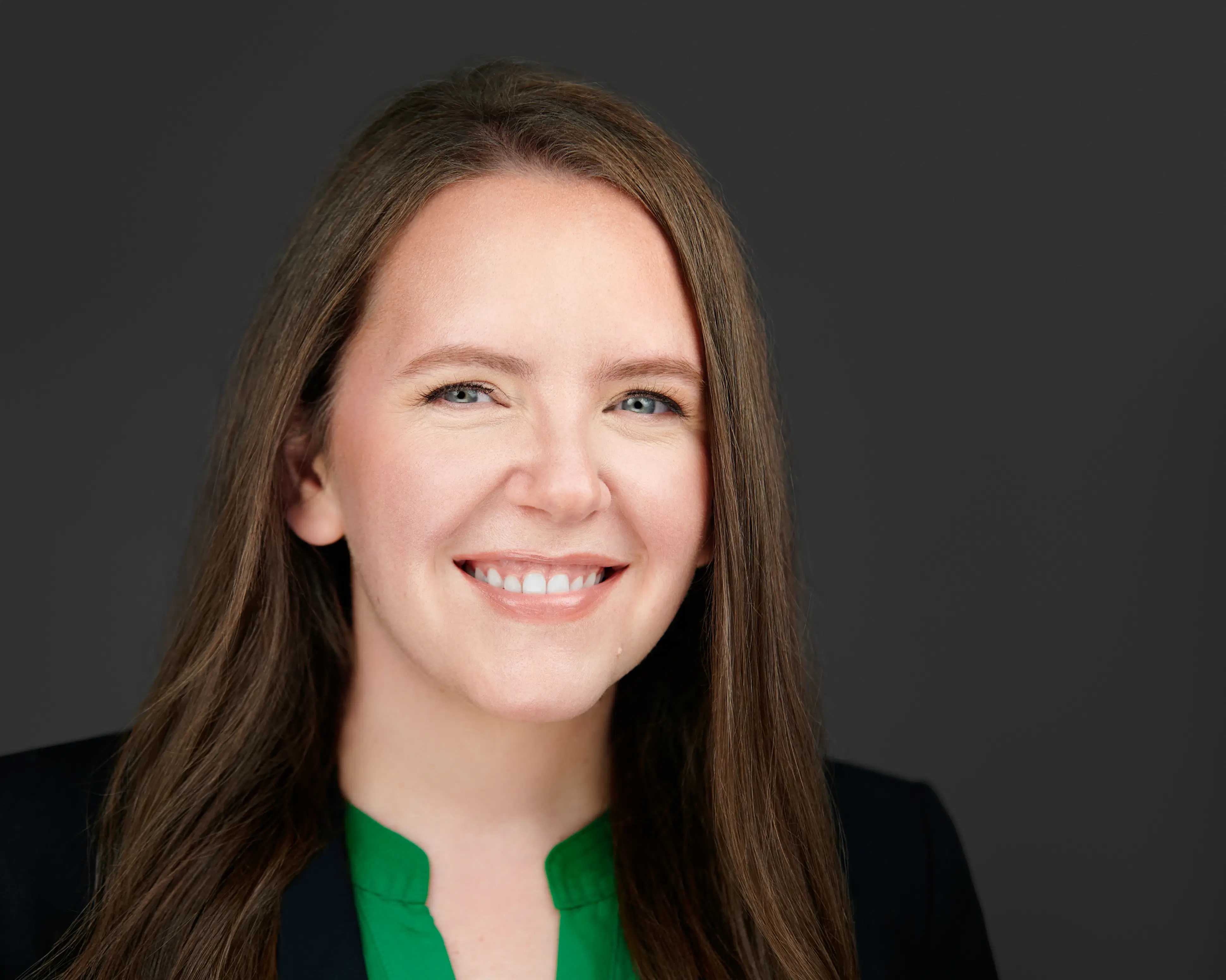 Confident executive headshot featuring a woman with a natural smile and direct eye contact