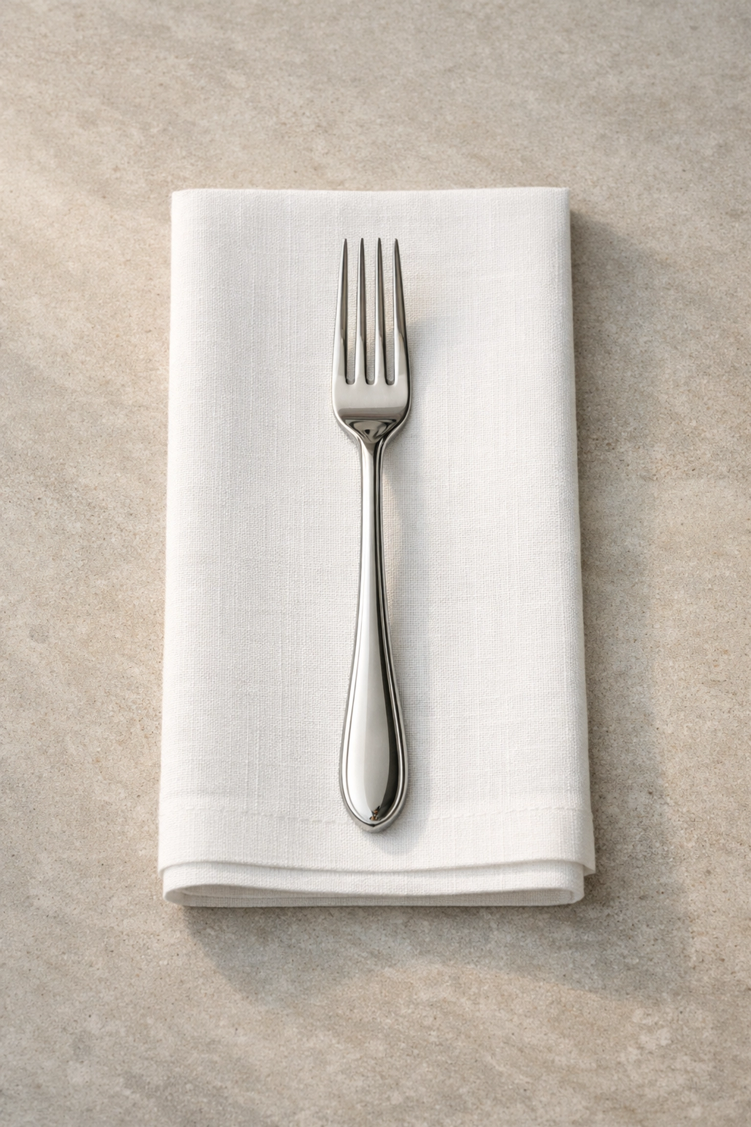 Perfectly aligned silver fork on a white linen napkin illustrating hospitality attention to detail.