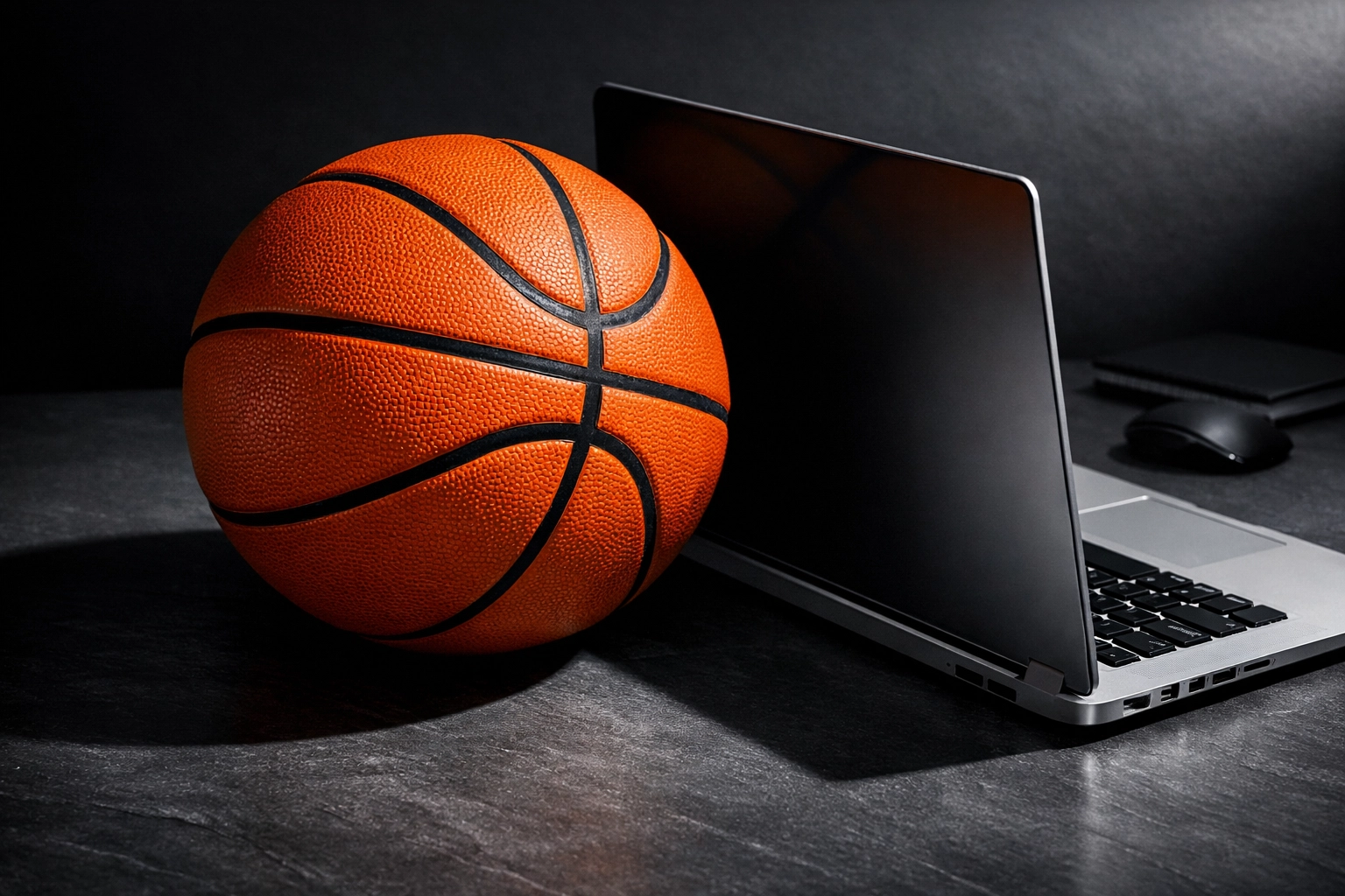 Basketball next to a laptop representing data-driven analysis of college athlete NIL market value.