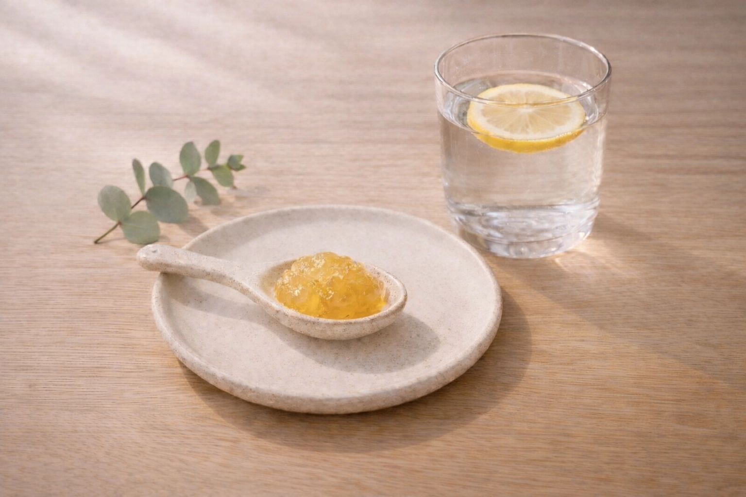 A spoonful of organic sea moss gel for a morning wellness ritual next to a fresh glass of lemon water.