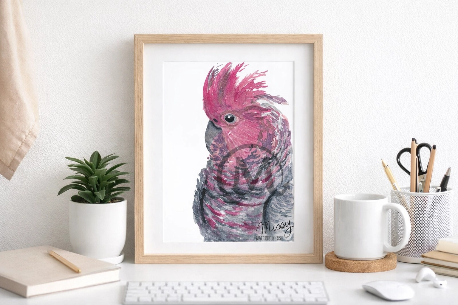 Missy's original Pink Cockatoo watercolor print in a physical home office mockup with visible watermark and signature