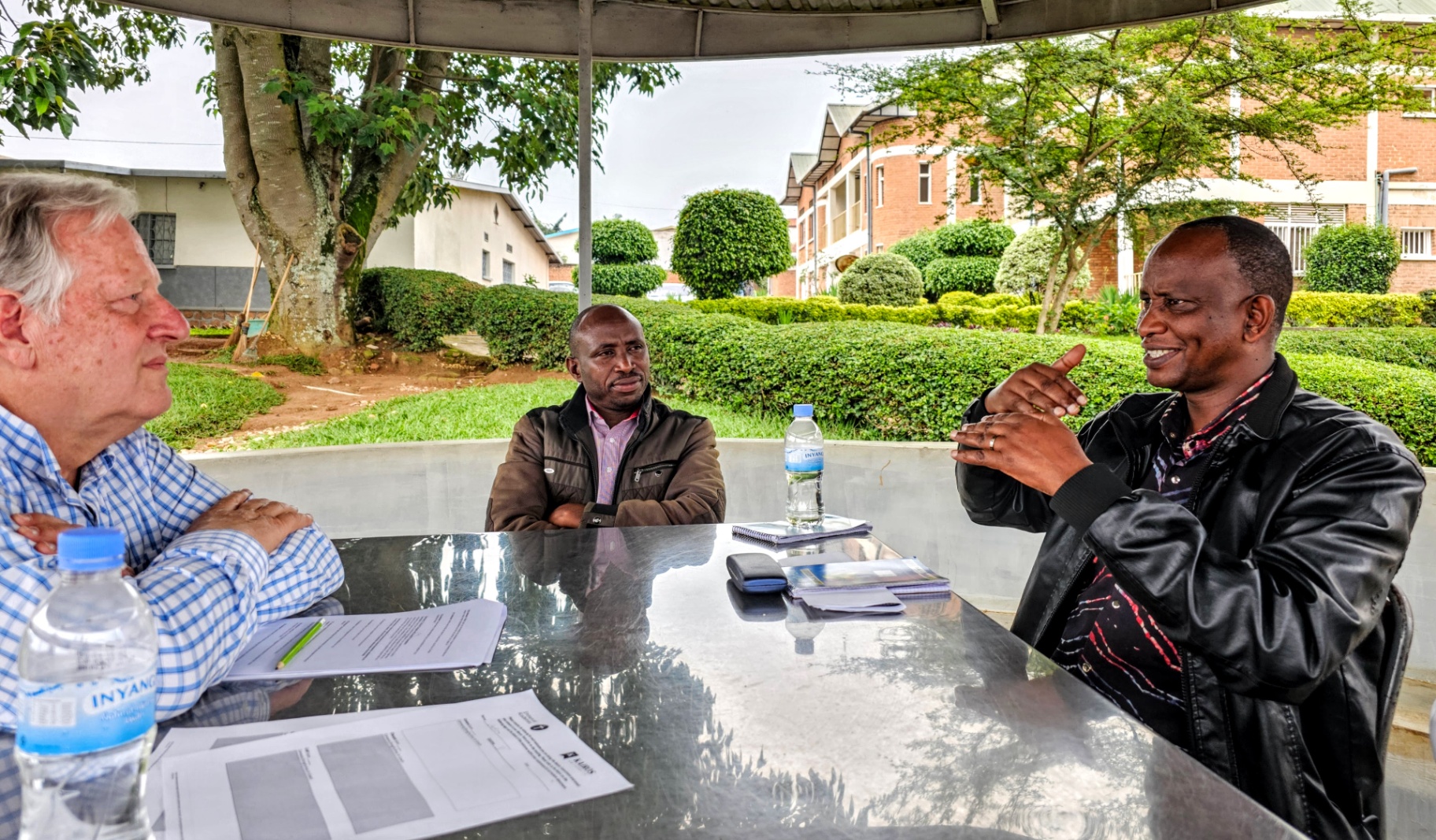 Three men discussing theological education outdoors