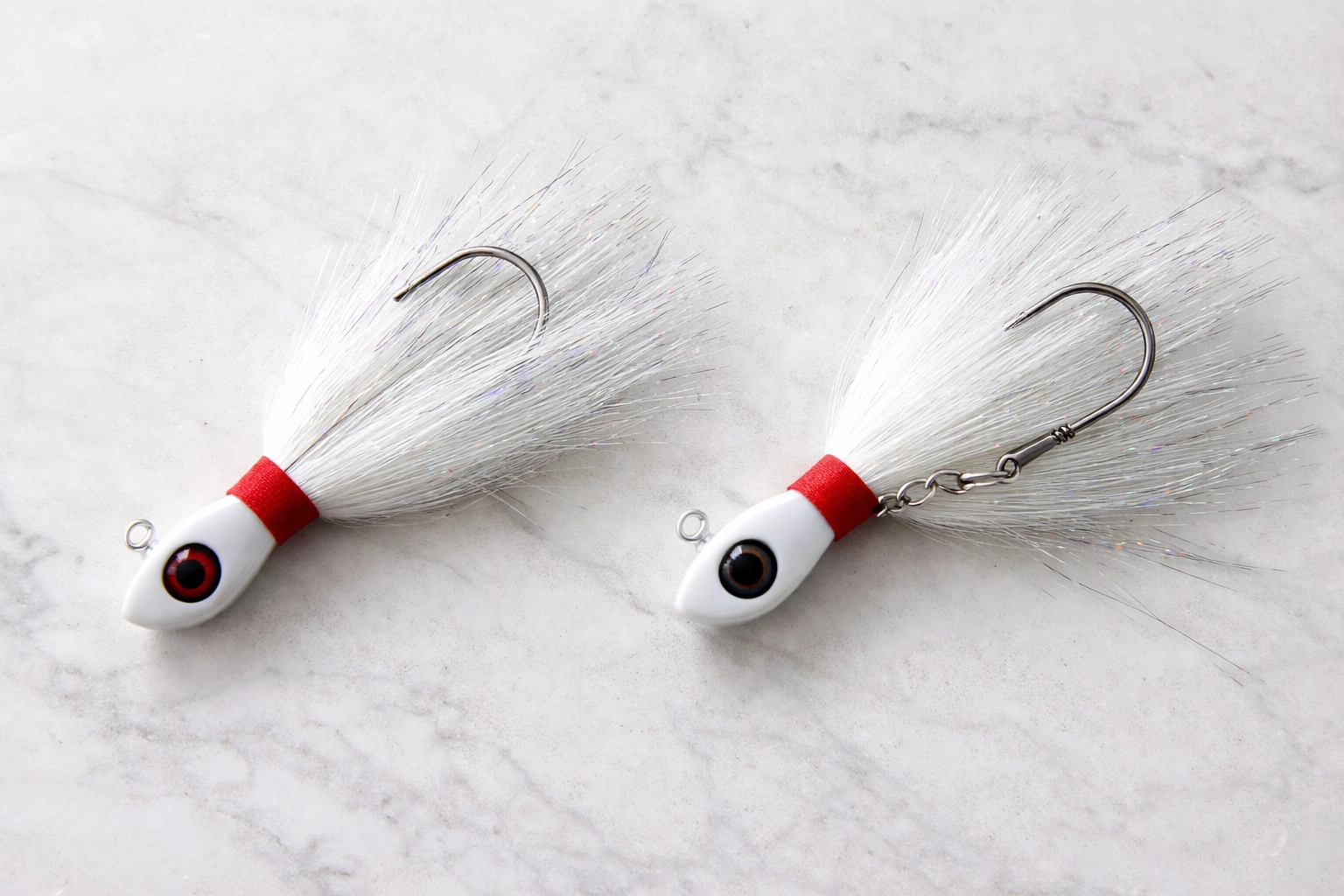 Side-by-side comparison of fixed hook and swing hook bucktail jigs on a marble surface