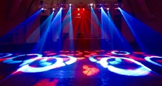 Custom DJ Lighting Setup by Modish Entertainment Custom DJ lighting setup featuring vibrant red and blue spotlights, pattern projections, and professional stage effects, highlighting Modish Entertainment's upscale event atmosphere and high-end audiovisual production for weddings, parties, and corporate events.