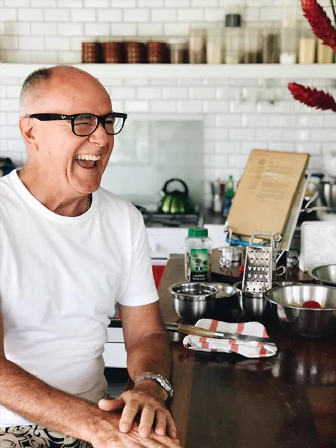 A smiling, confident coach in a well-organized home kitchen, ready to guide aspiring culinary entrepreneurs.