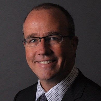Middle-aged man in suit with glasses representing investment partner expertise.