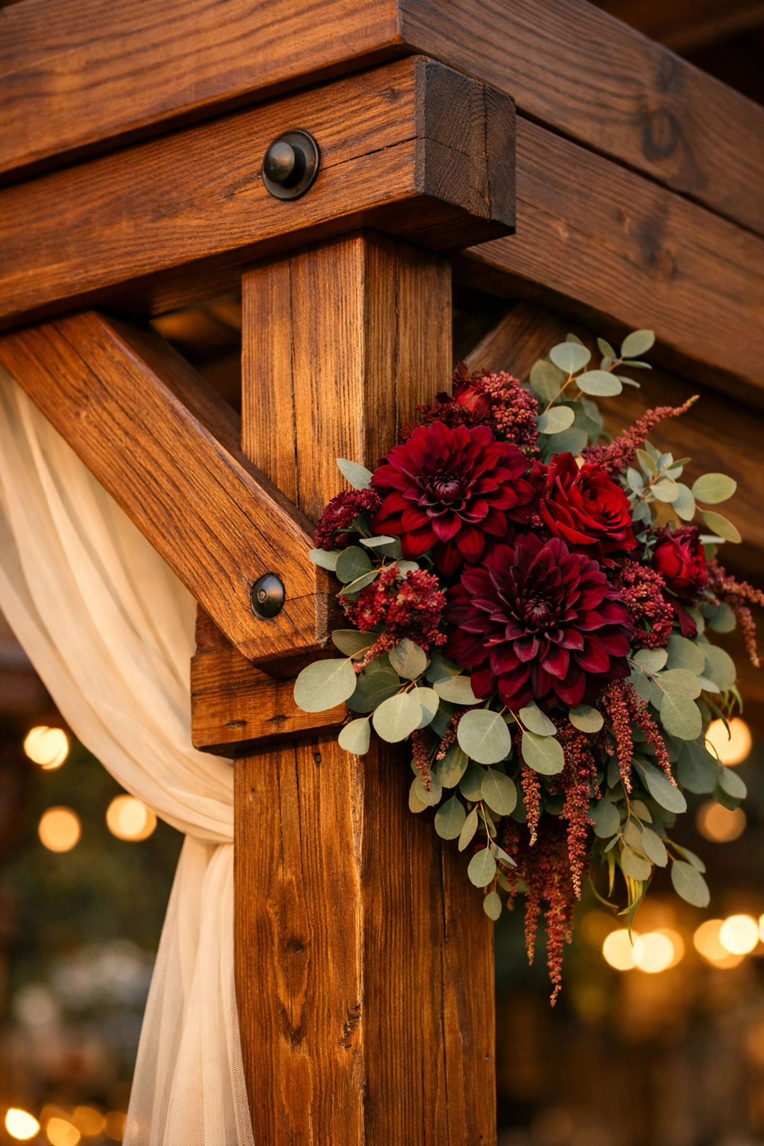 Close-up of a refined stained-timber wedding arch rental with lush dahlias and eucalyptus floral decor.