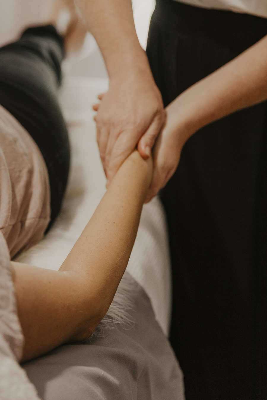 A beauty therapist gently holds and massages a client's arm