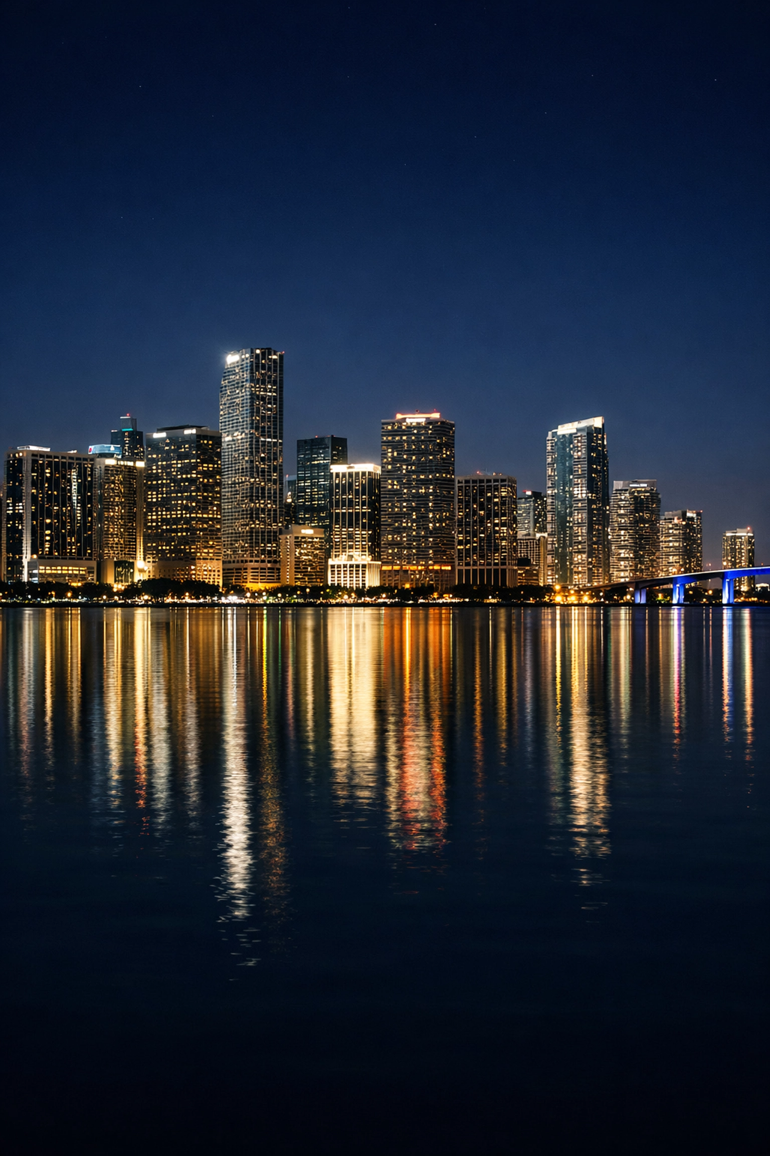 Long-exposure shot of the glowing Miami skyline reflecting on Biscayne Bay near the best miami beaches.