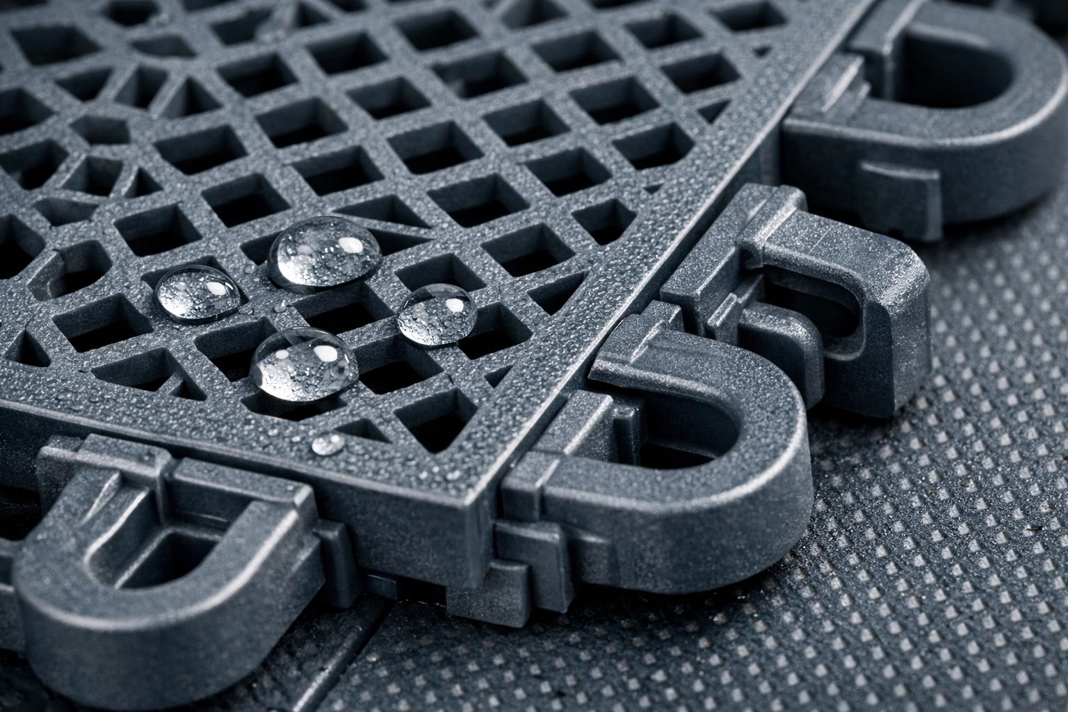 Close-up of interlocking grey modular sports tiles with perforated drainage for outdoor basketball courts.