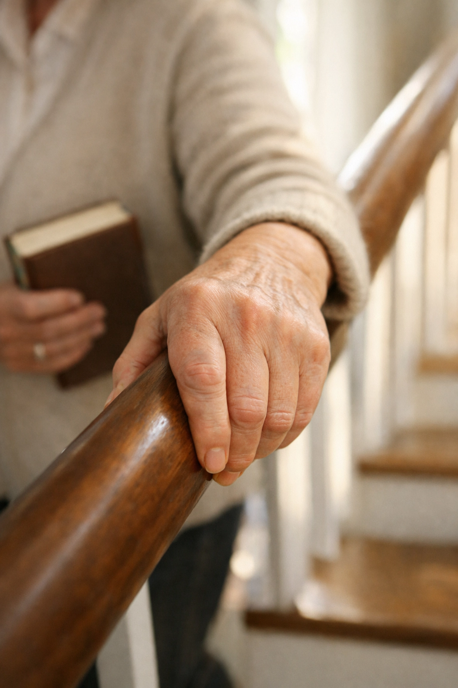 A senior’s hand using a secure power grip on a sturdy round handrail while descending stairs.