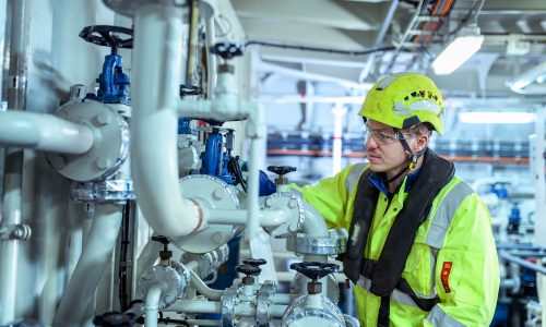 Engineer inspecting and maintaining industrial piping and valve systems