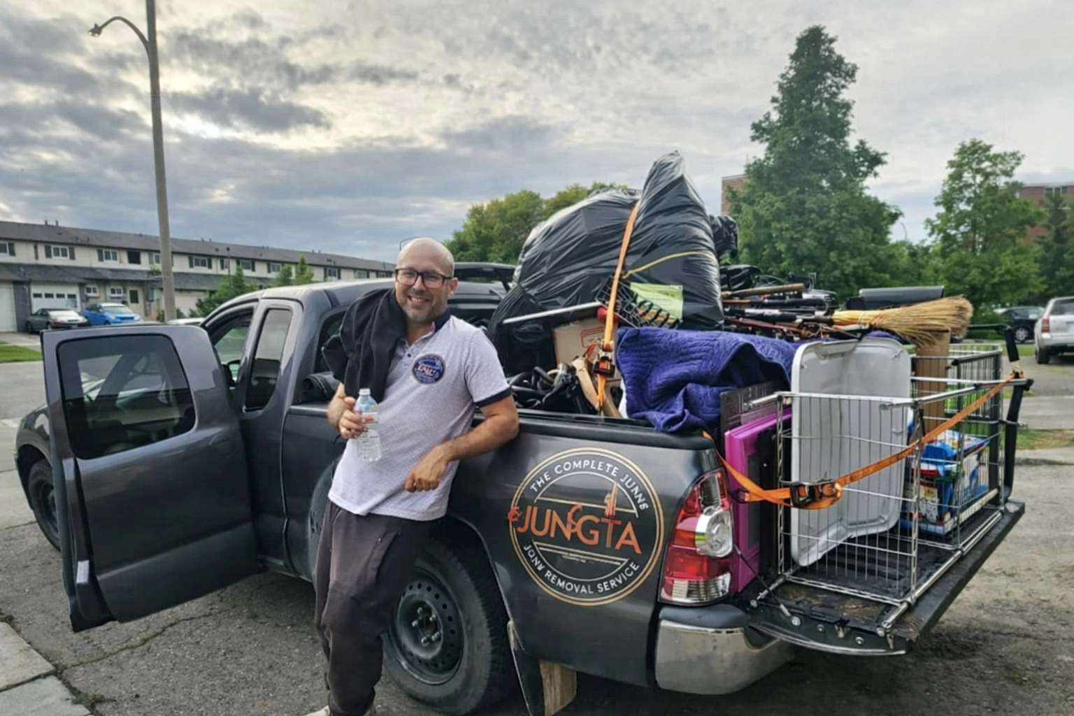 Roman, owner of Junk GTA, standing by his truck loaded with junk for removal in a residential neighborhood