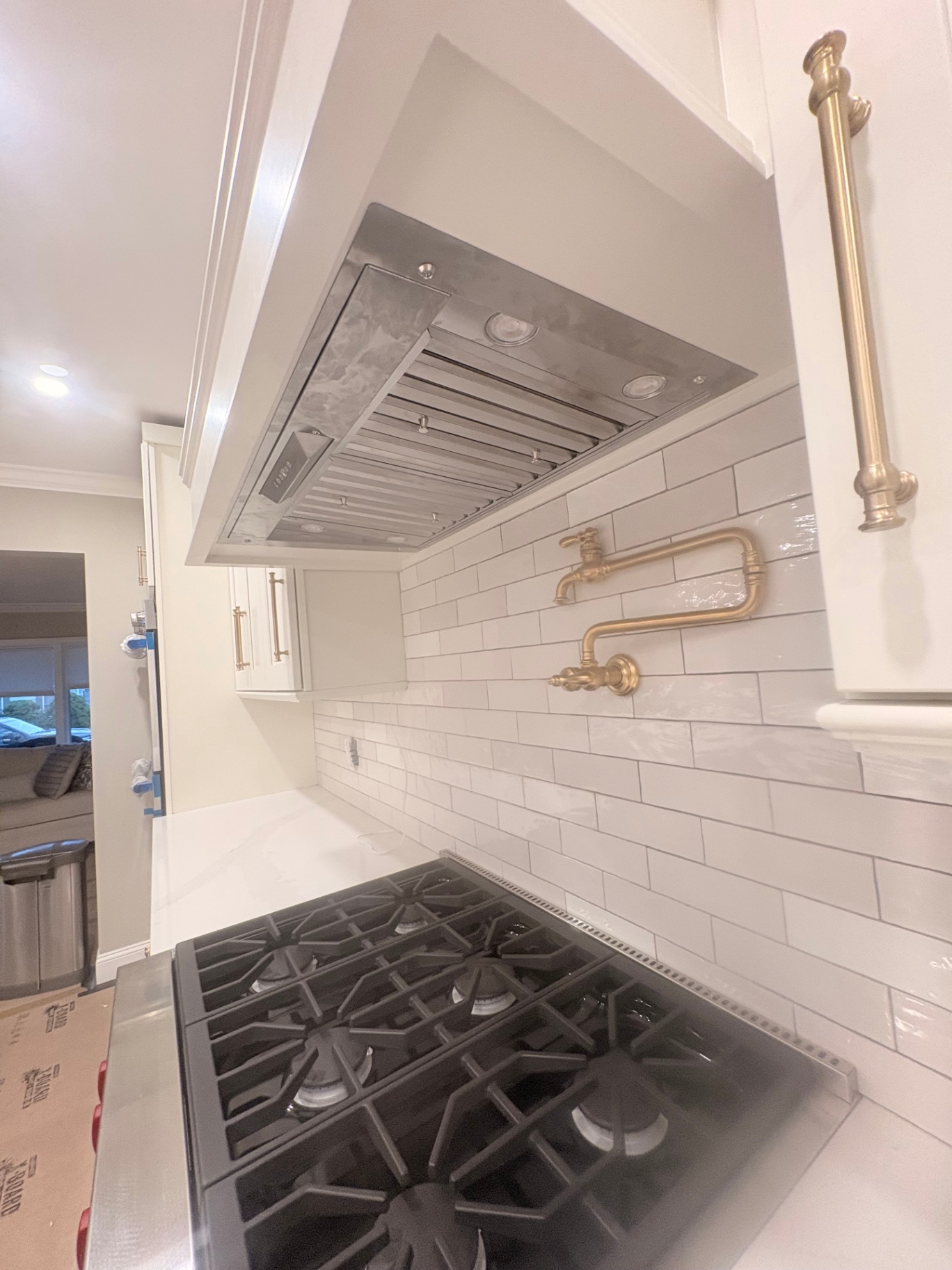 Custom Kitchen Design Custom kitchen design featuring a professional-grade gas range, sleek stainless-steel vent hood, white subway tile backsplash, and a brass pot filler. Cabinets and hardware are fully custom, designed and installed to client specifications. Countertops and millwork crafted in-house for a seamless, functional cooking space blending style and practicality.