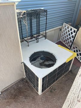Outdoor residential air conditioning condenser unit with visible debris buildup