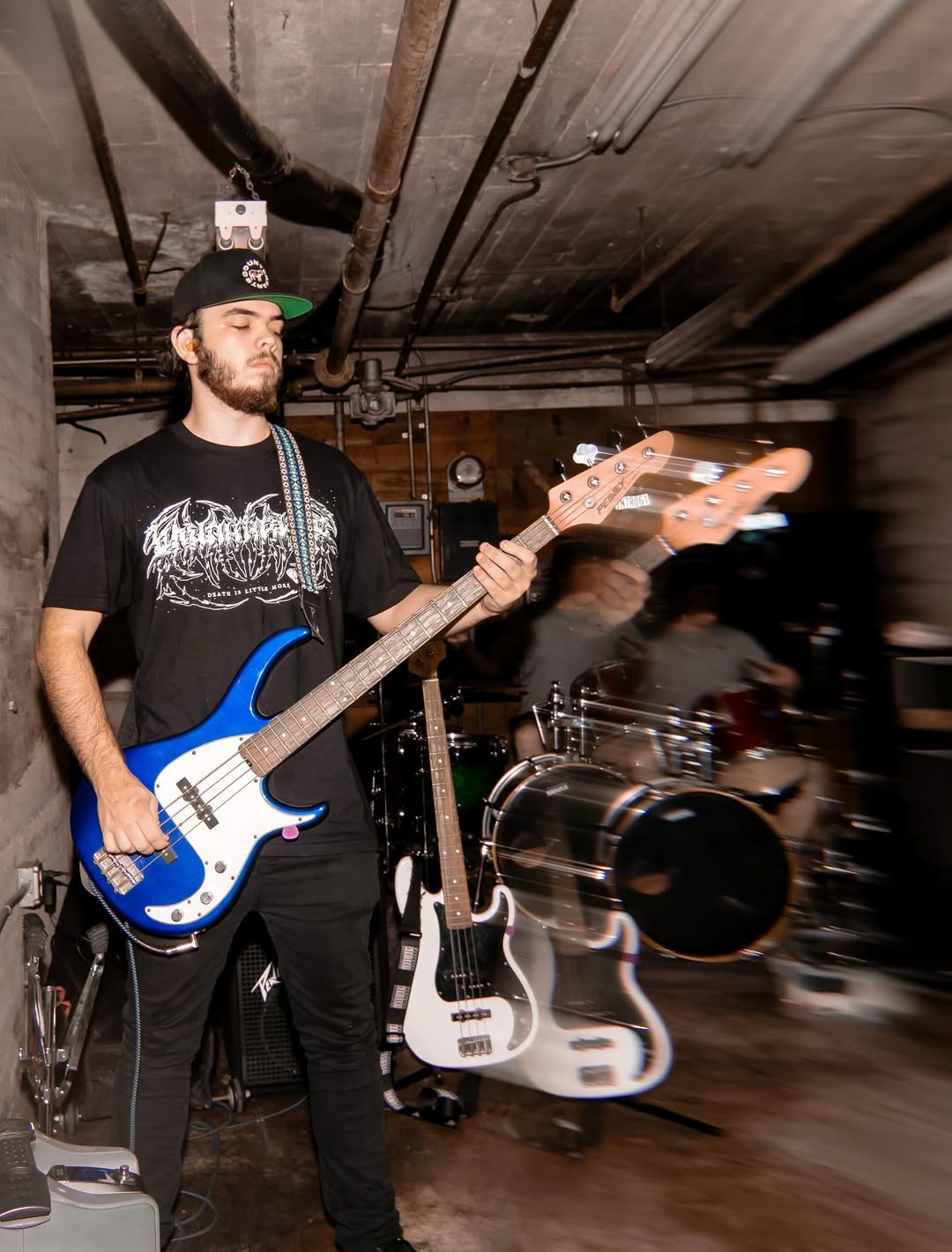 Musician performing live in underground venue A musician plays a blue electric bass guitar in an intimate, underground venue.