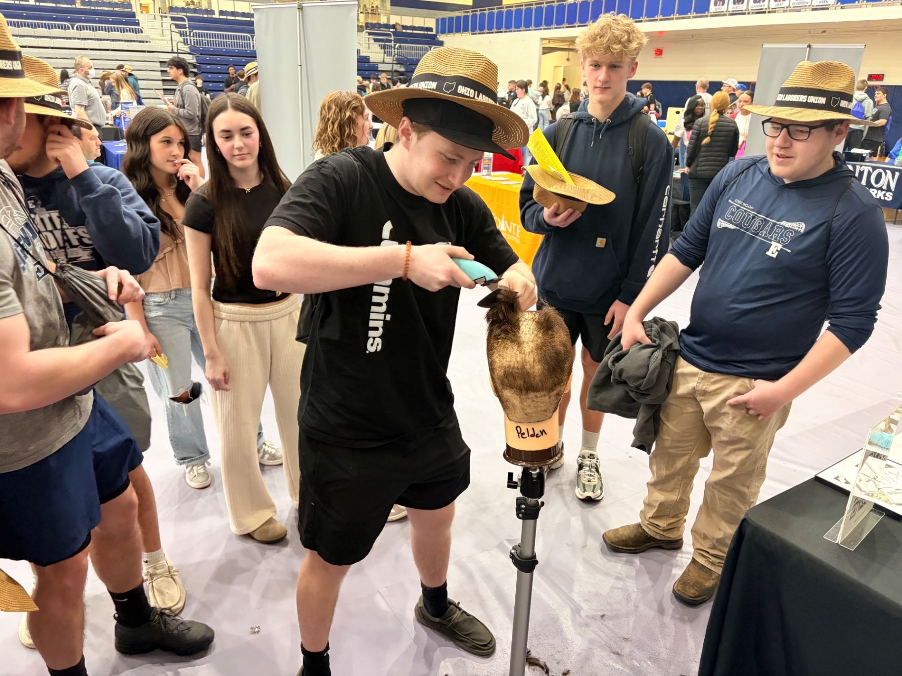 Clipper close-up demo during Edgewood High School Career Fair barbering booth, hands-on technique discussion, tool control, safety focus.