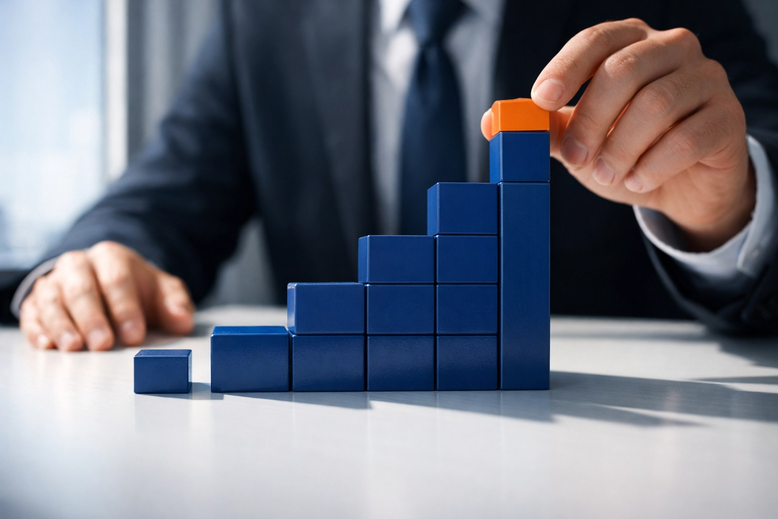 Hands building ascending blocks representing business growth milestones and progressive goal achievement