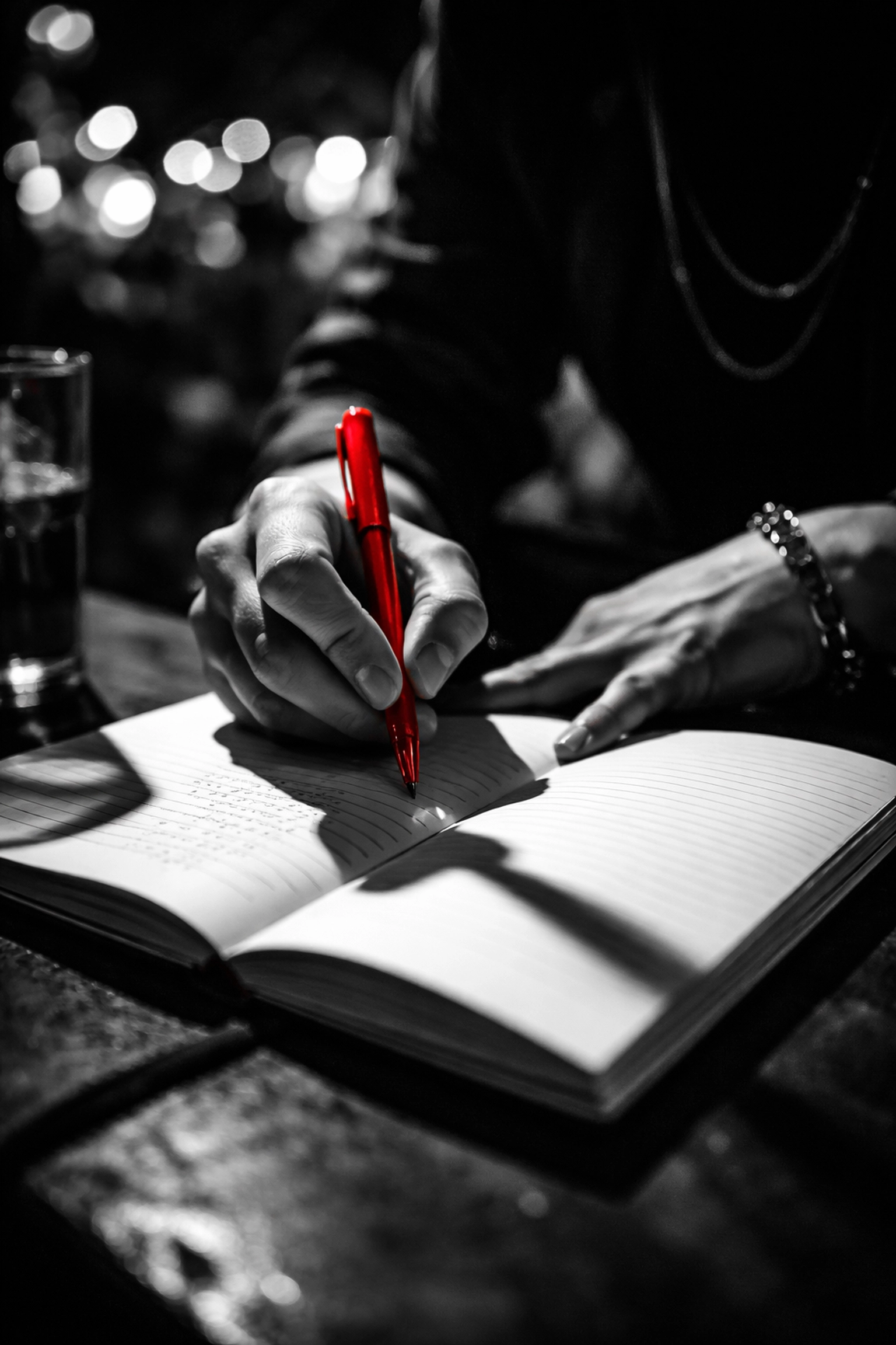 Close-up of hands writing poetry in an intimate spoken word session, highlighting creative self-expression.