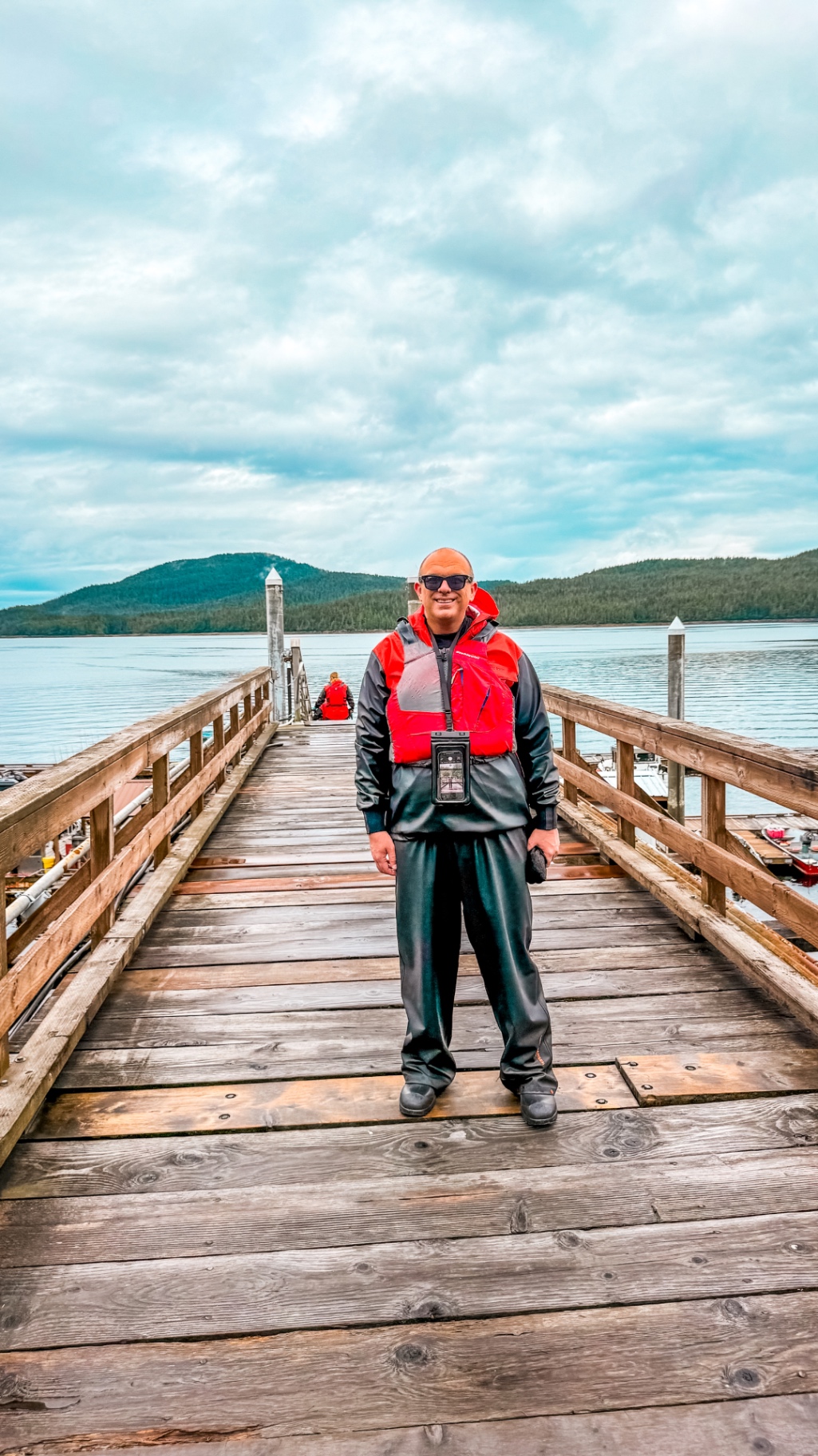 John Perri on the dock in Ketchikan wearing a red life vest and expedition gear